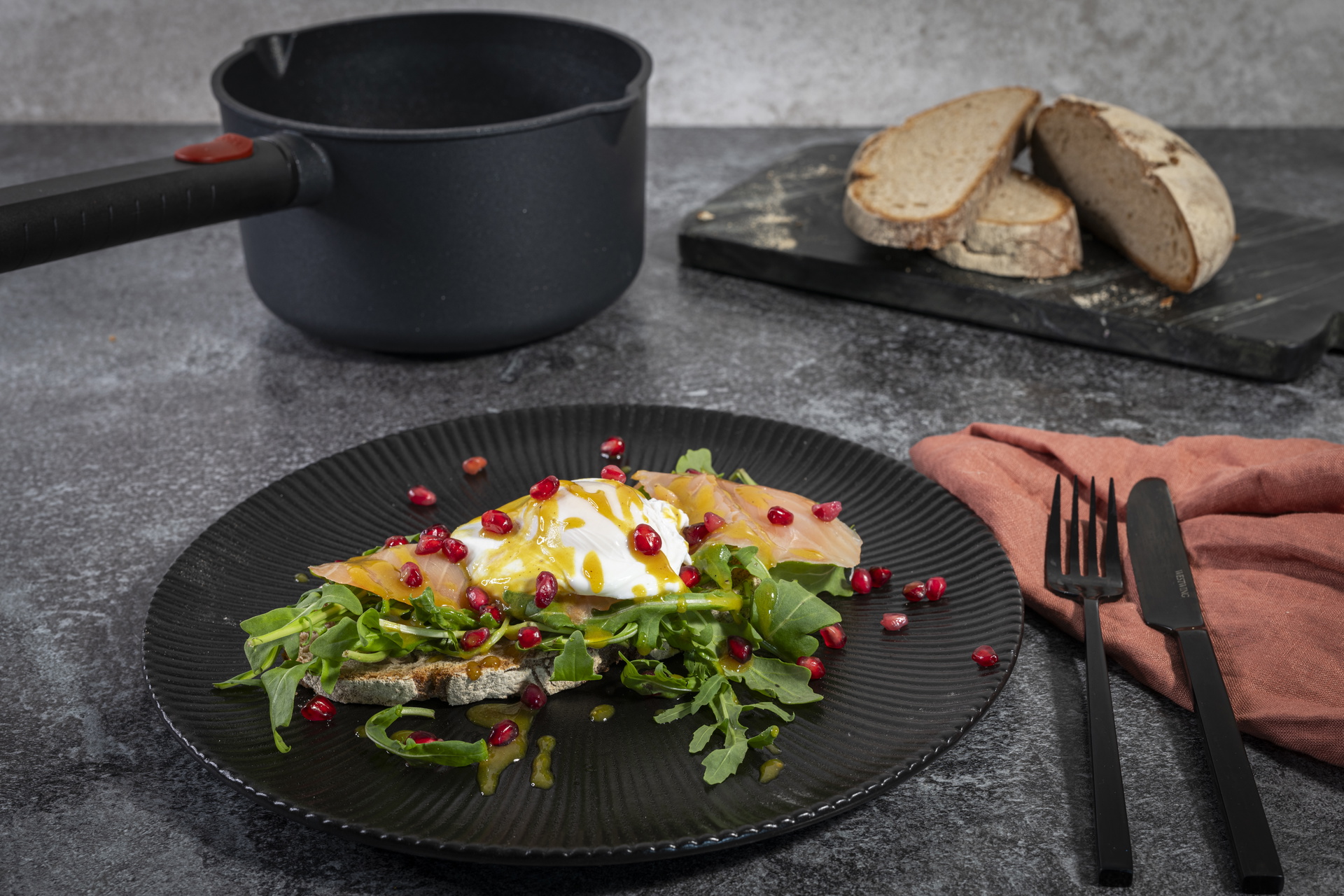 Auf einem Teller liegen pochierte Eier, dahinter steht ein runder Logic XR Stieltopf.