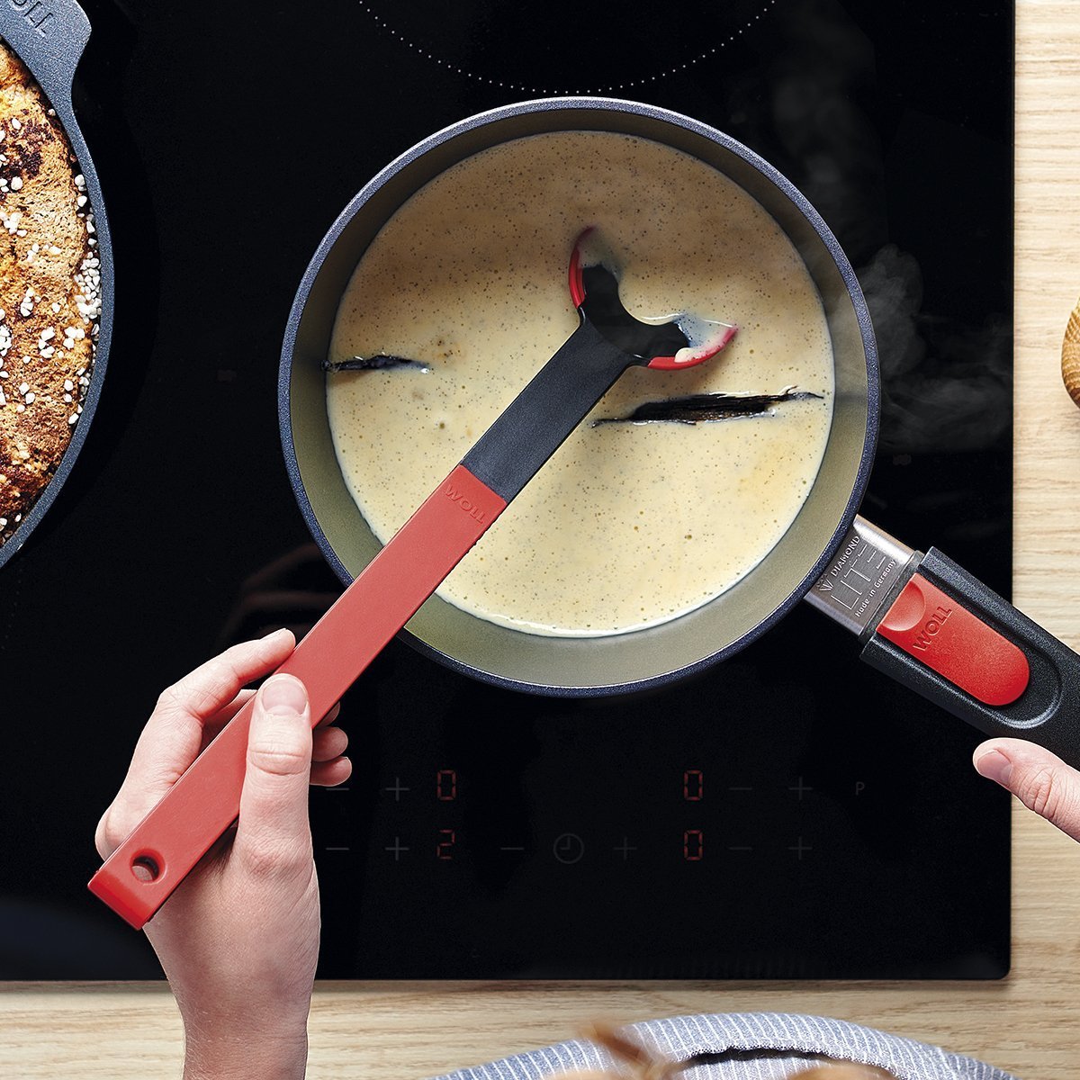 KU005_Mood_1200x1200_RGB In einem runden Diamond Lite Stieltopf wird Vanillesauce gekocht und mit einem roten Cock it Lochlöffel umgerührt.