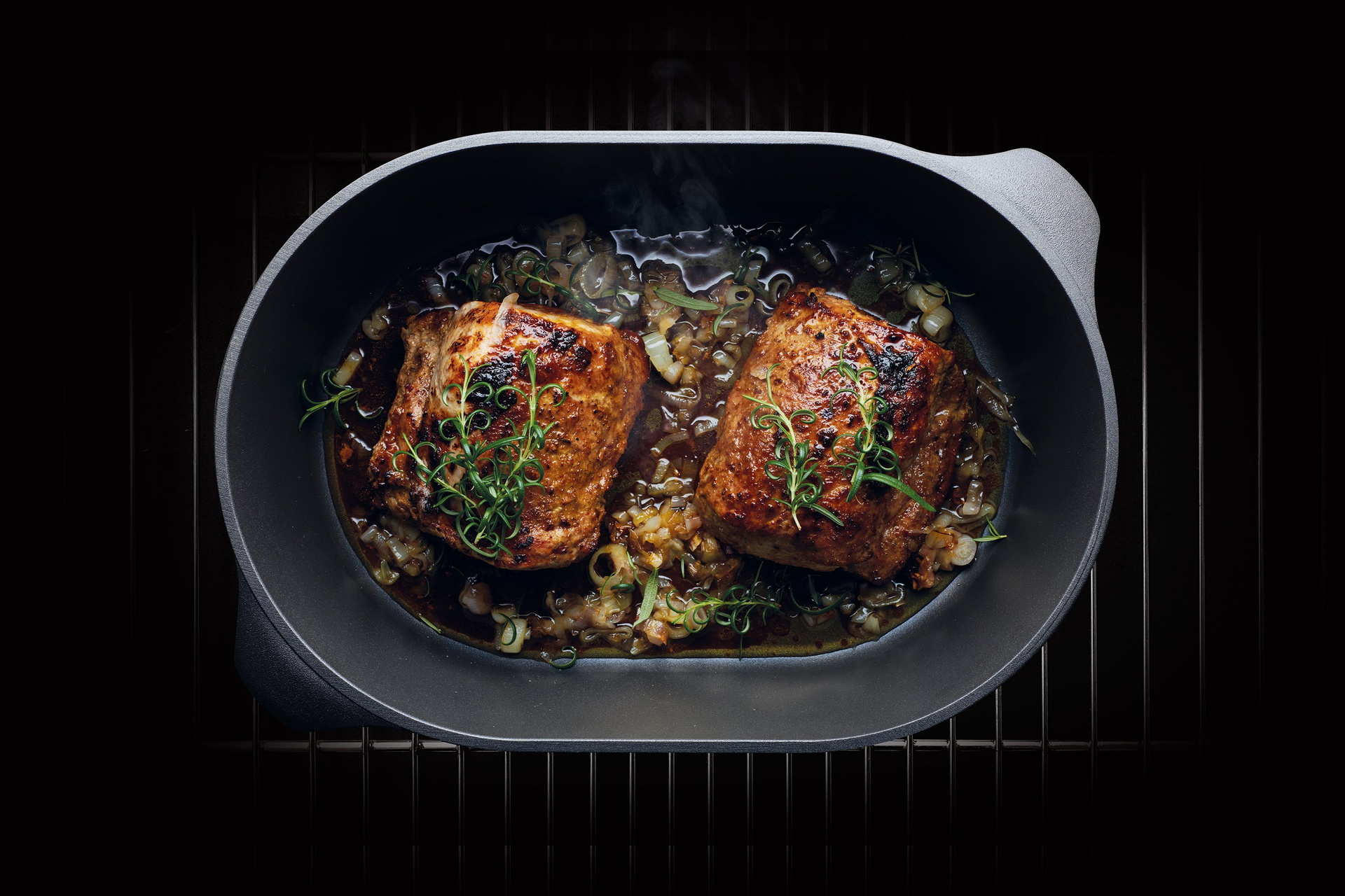 Auf einem Rost steht ein heißer Bräter der Serie Titan Best. In diesem befinden sich frisch gebratene Schweinelende.