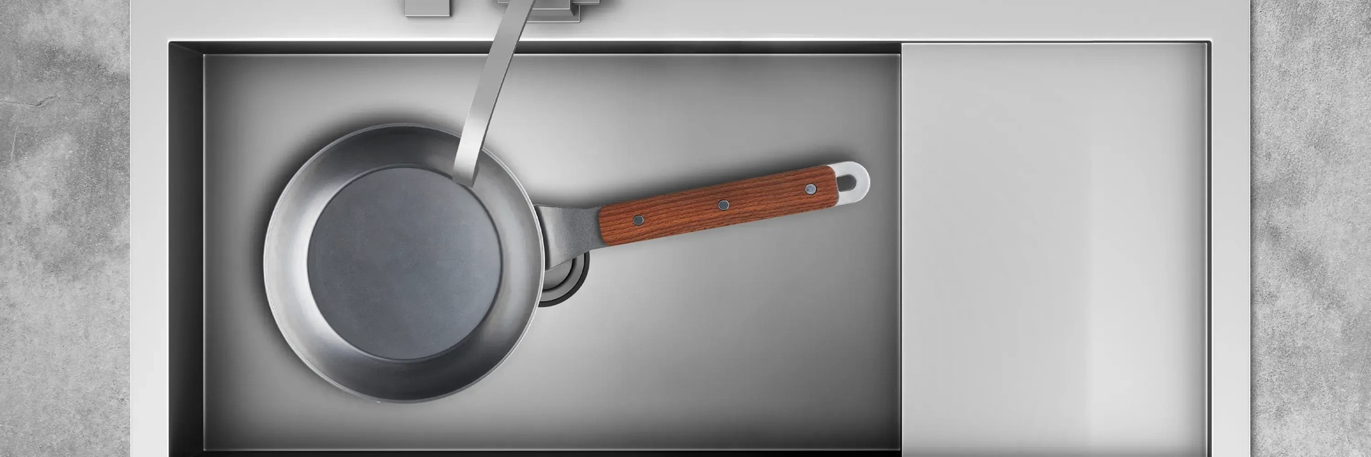 In einem Spülbecken liegt eine runde Carbon Steel Pfanne mit festem Holzstiel.