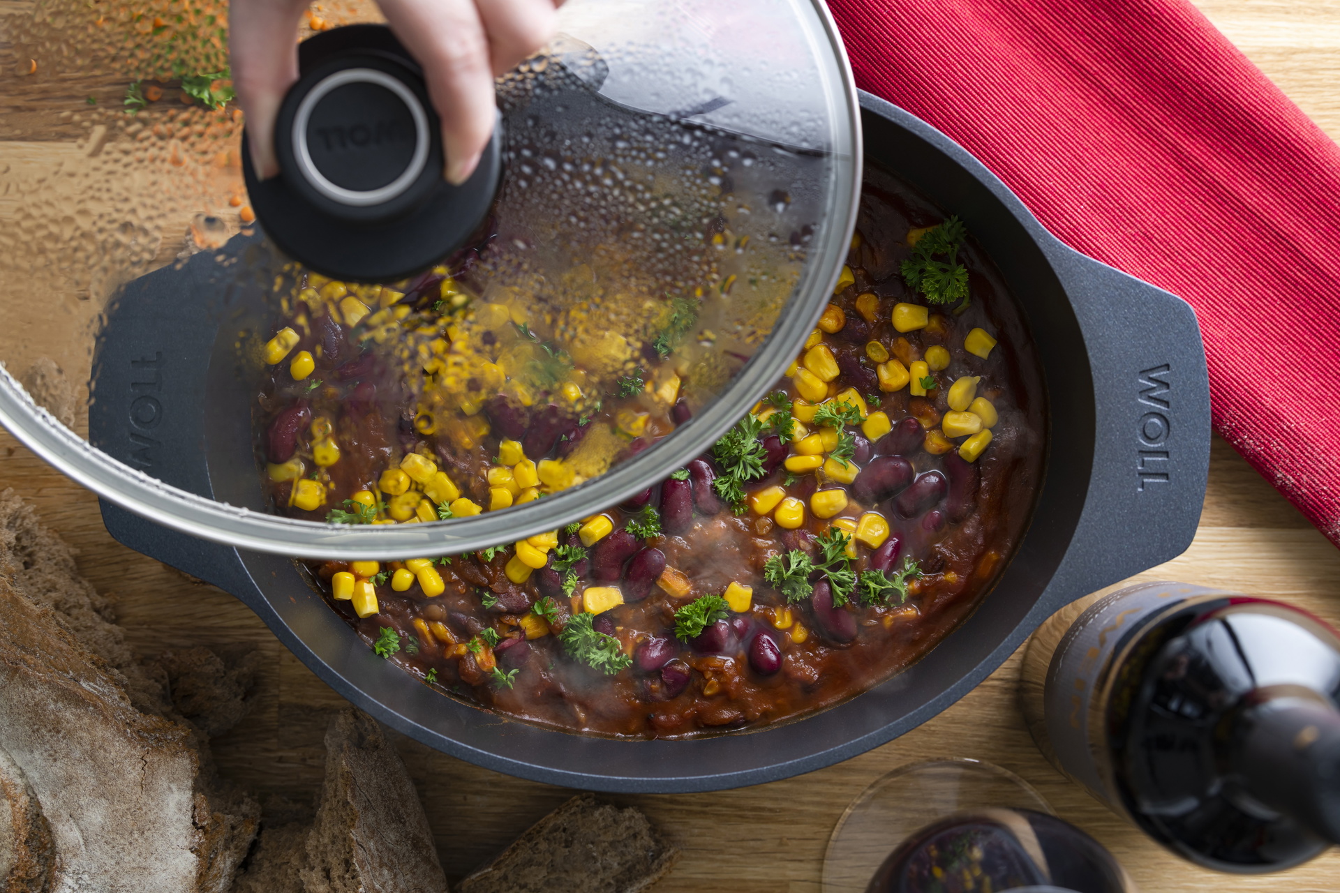 Ein Gussbräter der Serie Diamond Lite enthält Chili con Carne, daneben steht eine Flasche und ein rotes Tuch liegt daneben.
