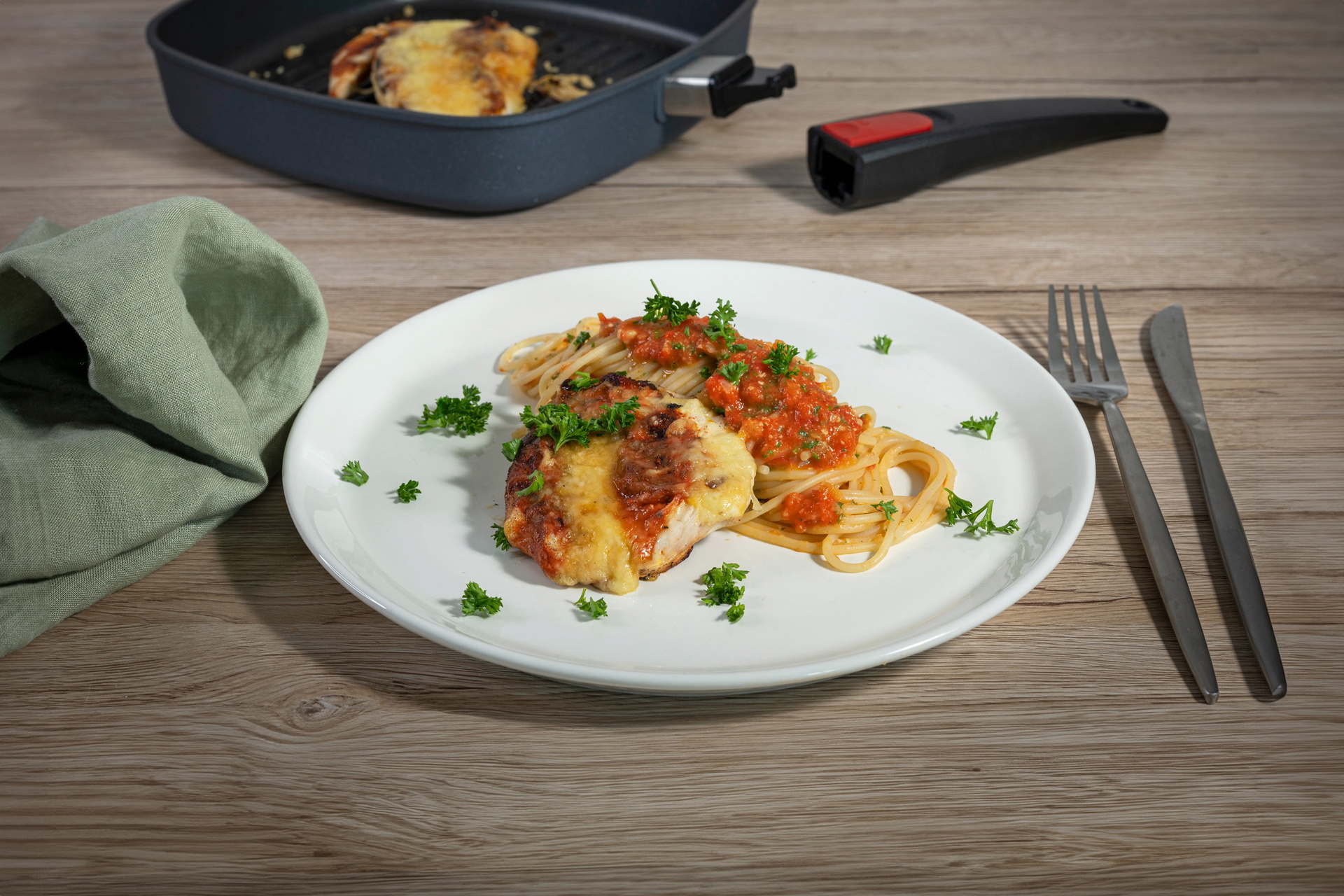 In einer viereckigen Grillpfanne der Serie „Diamond Lite“ mit abgenommenem Stiel befindet sich überbackenes Hähnchen. Auf einem Teller wurde das überbackene Hähnchen mit Pasta angerichtet.