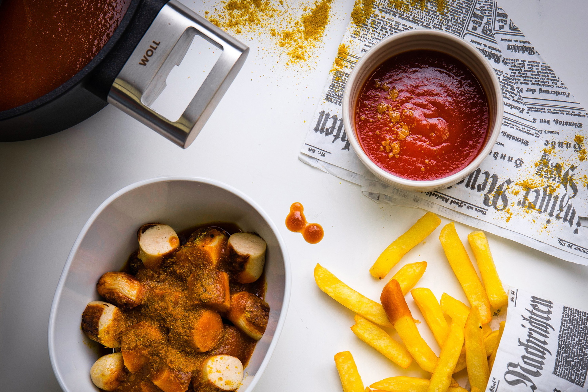 Die Currysauce wurde in einem Logic-Topf zubereitet. In einer Schüssel befindet sich die fertige Sauce. Darunter steht eine weitere Schüssel mit frisch zubereiteter Currywurst. Daneben liegen Pommes.