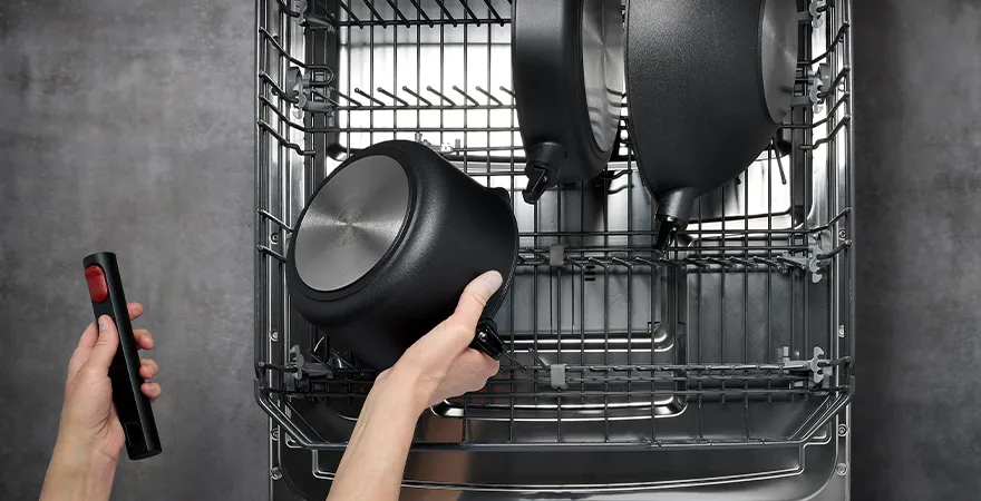 In der Spülmaschine werden verschiedene Geschirre mit abgenommenem Griff dargestellt. Links darunter ist der abnehmbare Griff zu sehen.