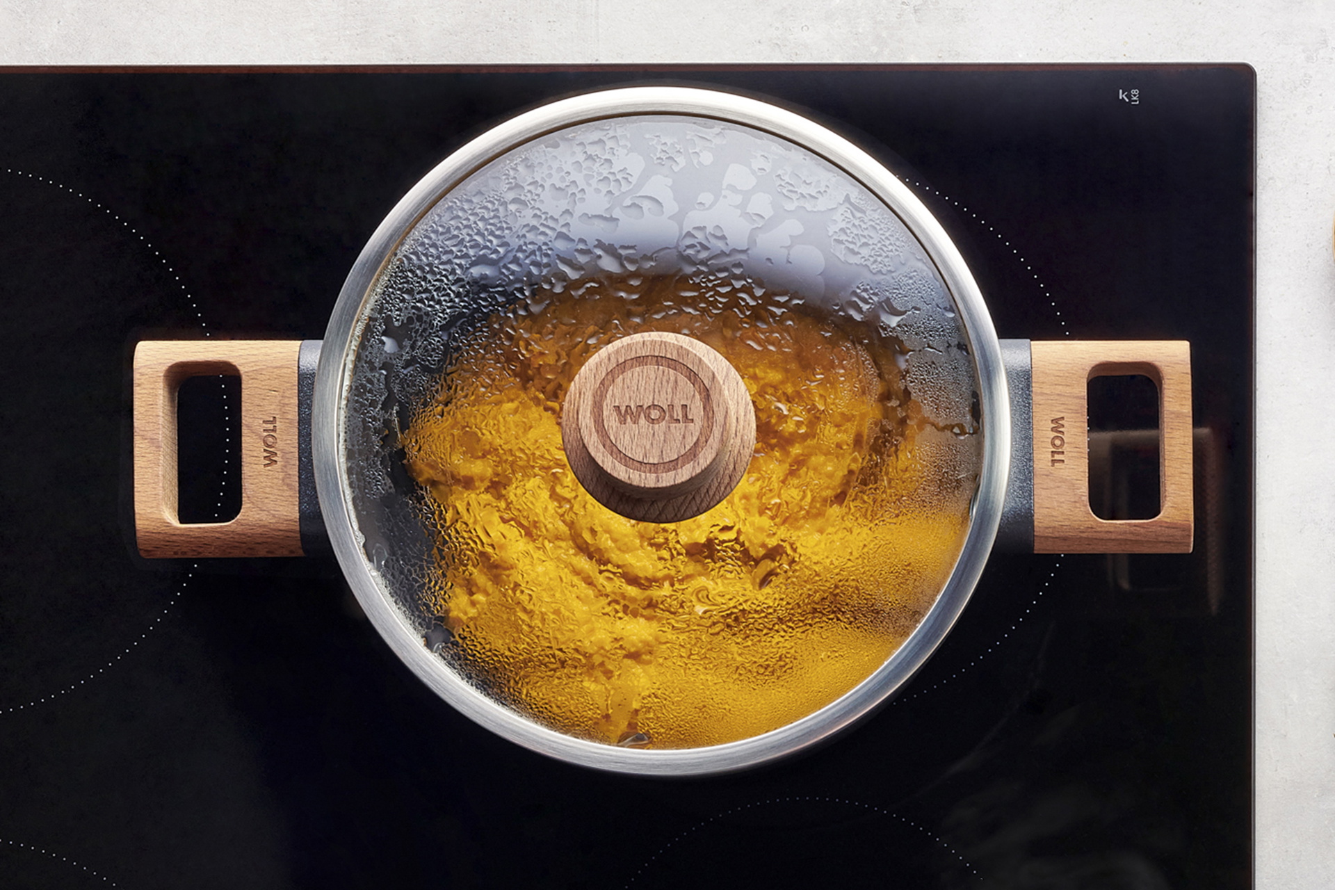 Auf dem Herd steht ein runder Eco Logic QXR Topf, in dem sich ein dampfendes Gericht befindet. Am Glasdeckel hat sich Kondenswasser gebildet.