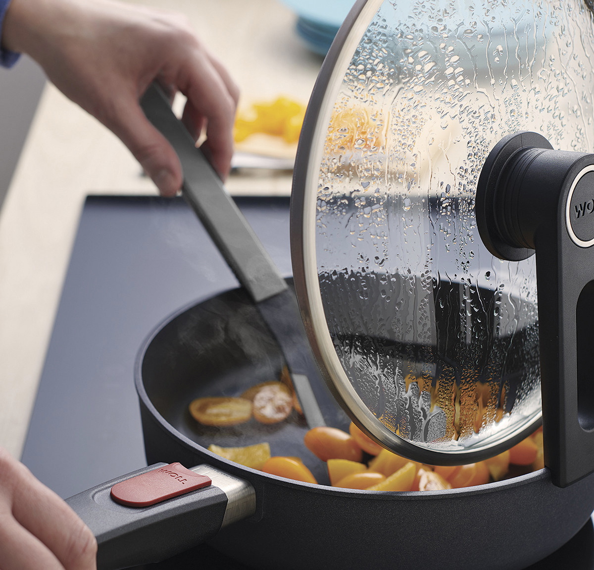 Cook it Pfannenwender In der runden Diamond Lite Pfanne wird ein Gericht mit einem grauen Cock it Pfannenwender umgerührt. Der Smart Lid steht auf der Pfannenkante.