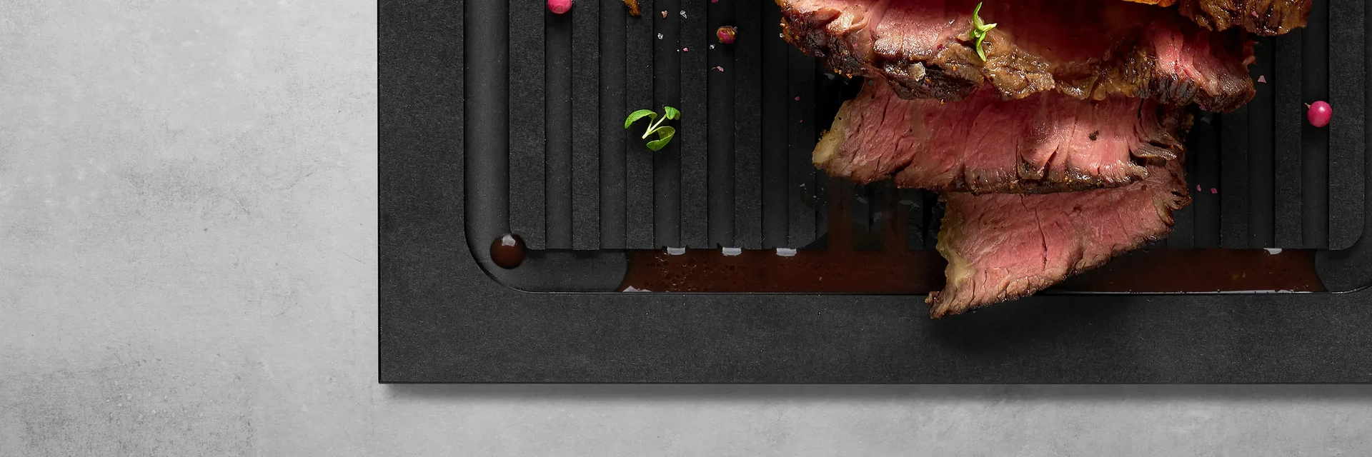 Ein Stück Fleisch wurde in Streifen geschnitten. Der dabei austretende Fleischsaft läuft in die Rillen des Schneidebretts der Serie Cut & Serve.