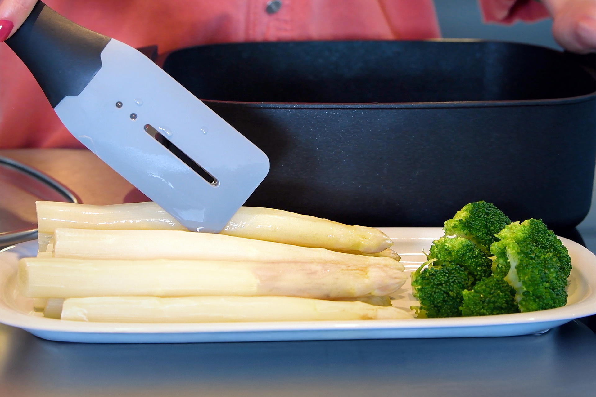 Der Spargel wurde in einem Bräter der Serie Eco Logic QXR im Wasserbad gekocht und mithilfe einer Küchenzange der Serie Cock it auf einem Teller platziert.