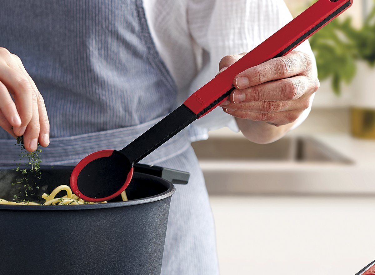 KU004_Mood_1200x880_RGB In einem Diamond Lite Topf werden frisch gekochte Nudeln mit einem roten Kochlöffel der Serie Cock it umgerührt und mit Kräutern garniert.