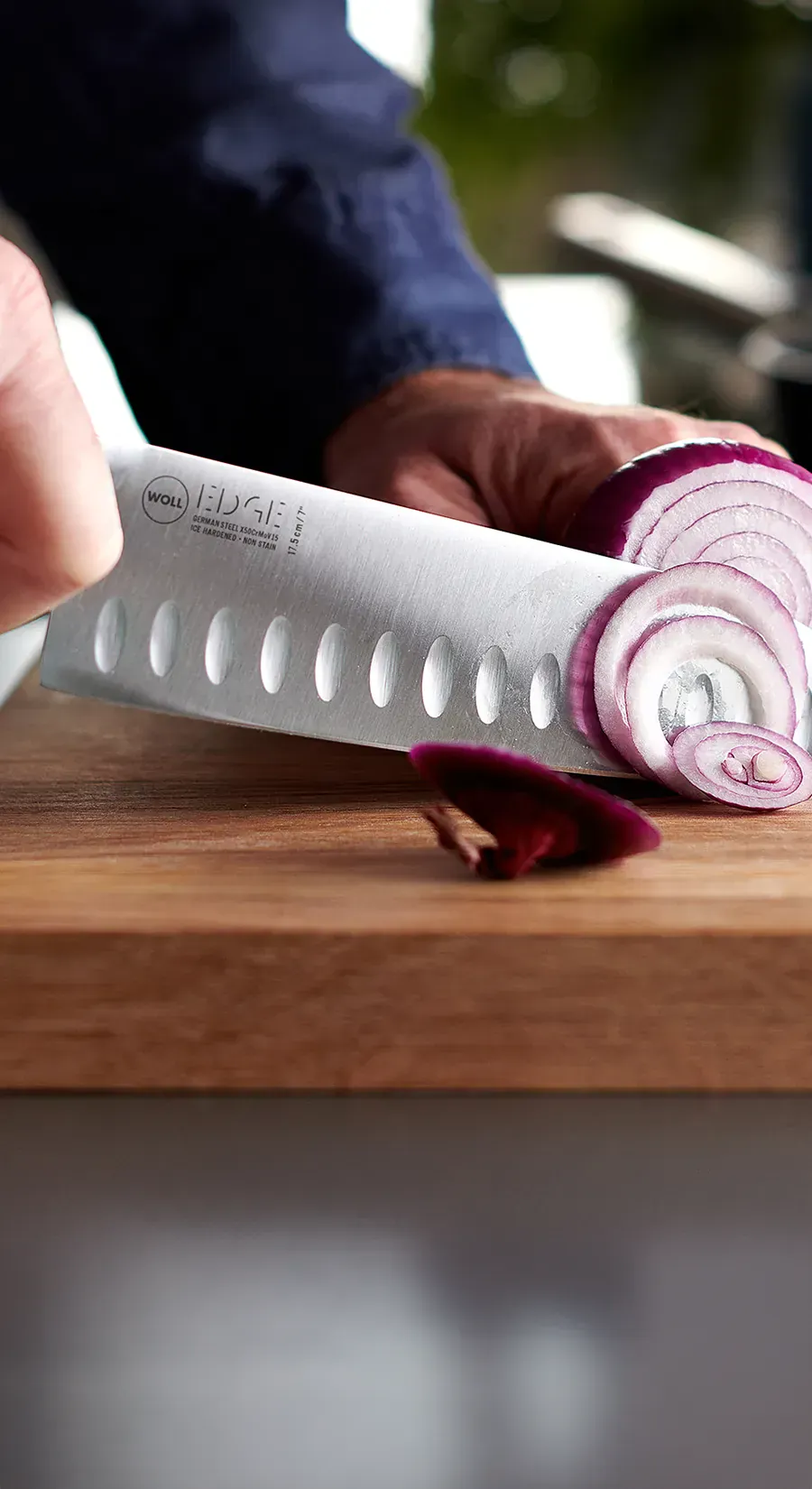 Auf einem Schneidebrett werden Zwiebeln mithilfe des Santokumessers der Serie Edge in dünne Scheiben geschnitten.