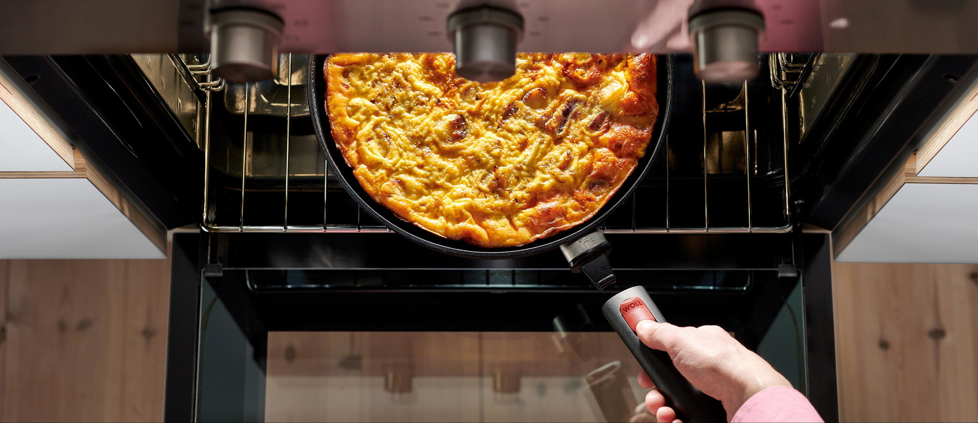 Eco Lite QXR Flachpfanne Auf dem Backofenrost steht eine runde Eco Lite QXR Pfanne mit gebackener Tortilla. Um die Pfanne zu entnehmen, wird der Stiel eingerastet.
