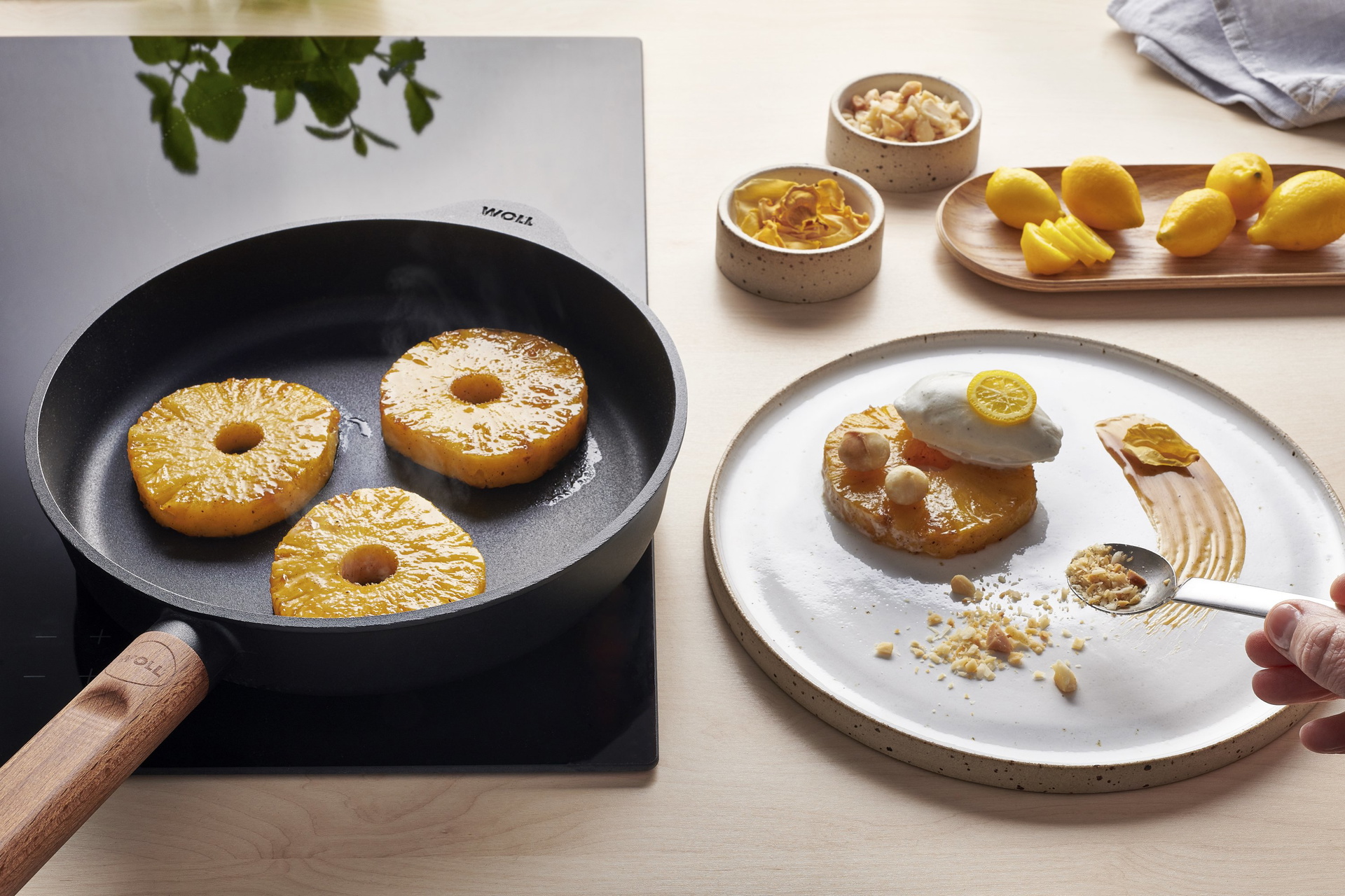 In einer runden Eco Logic QXR Pfanne werden Ananasscheiben angebraten und auf einem Teller mit Karamellsauce und Eis angerichtet.