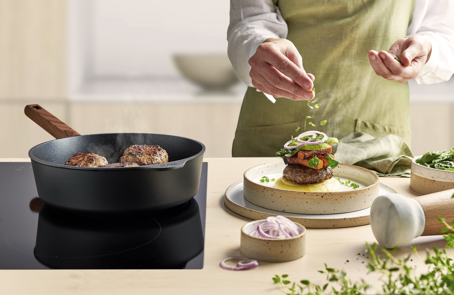 In einer runden Eco Logic QXR Pfanne werden Frikadellen angebraten und auf einem Teller platziert.