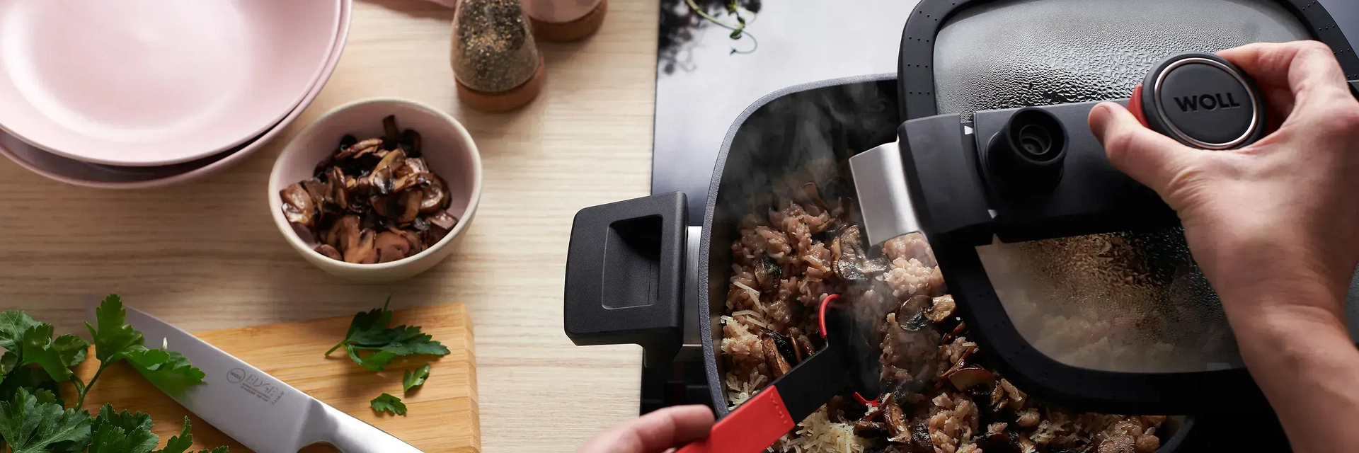 In dem Niederdrucktopf der Serie „Diamond Active Lite” wird ein dampfendes Reisgericht zubereitet. Der Glasdeckel wurde von einer Hand entfernt. In der Nähe stehen eine kleine Schüssel mit fertigen Pilzen, ein Holzbrett mit einem Messer der Serie Edge sow