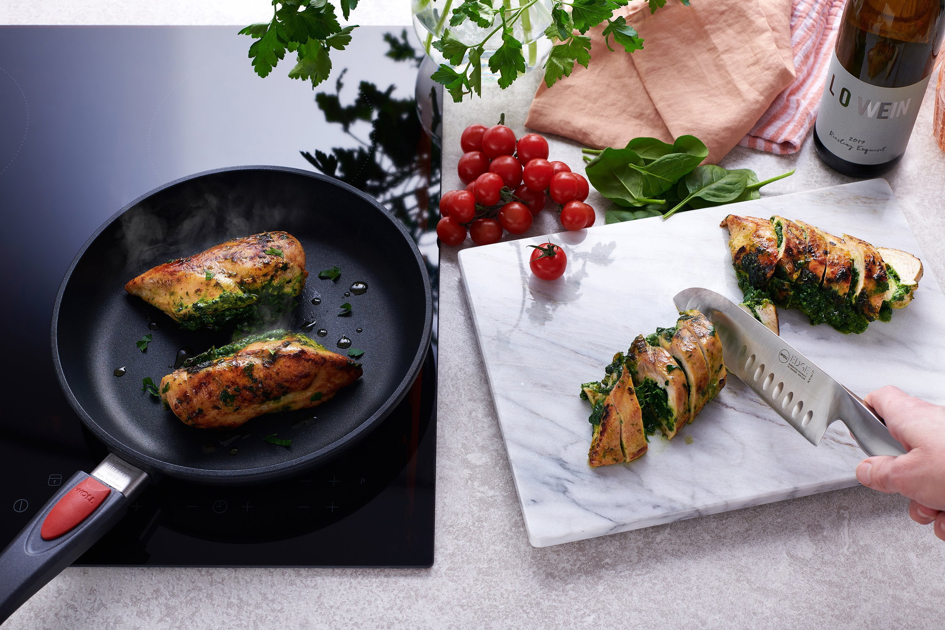 In einer runden, heißen Titan Best Pfanne werden Fleischrollen angebraten. Daneben wird mit einem Messer der Serie „Edge“ eine mit Spinat gefüllte Fleischrolle auf dem Schneidebrett in Portionsgrößen geschnitten.