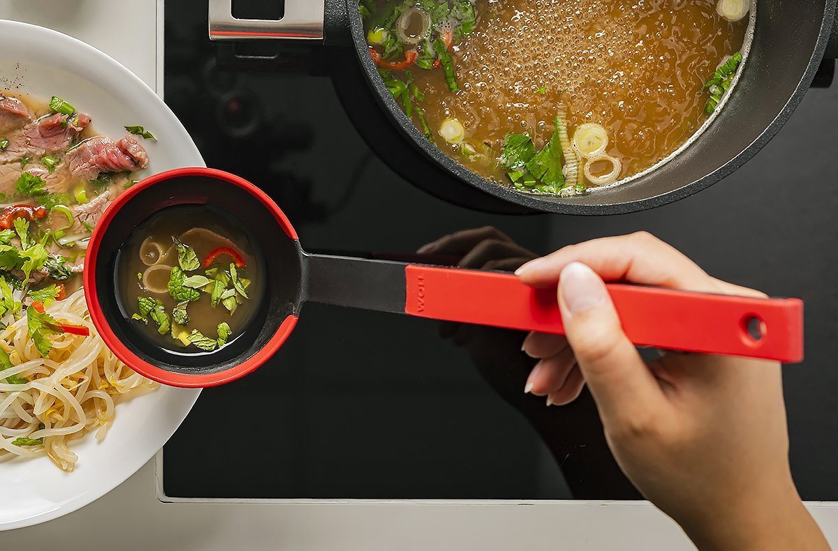 KU008_Mood_1200x790_RGB In einem runden Logic Topf befindet sich gekochte Brühe. Mit einer roten Cock it Schöpfkelle wird die Brühe über die Nudeln im Teller gegossen.