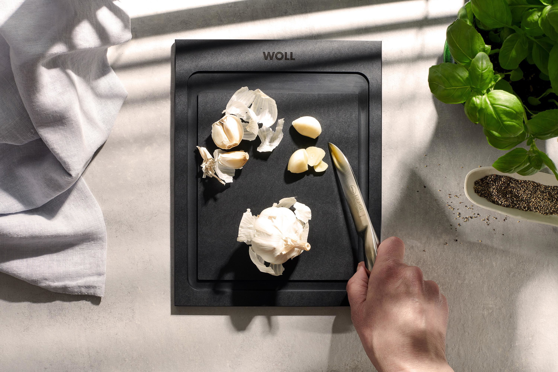 Auf einem Cut & Serve Schneidebrett mit Saftrinne liegen Knoblauchzehen.