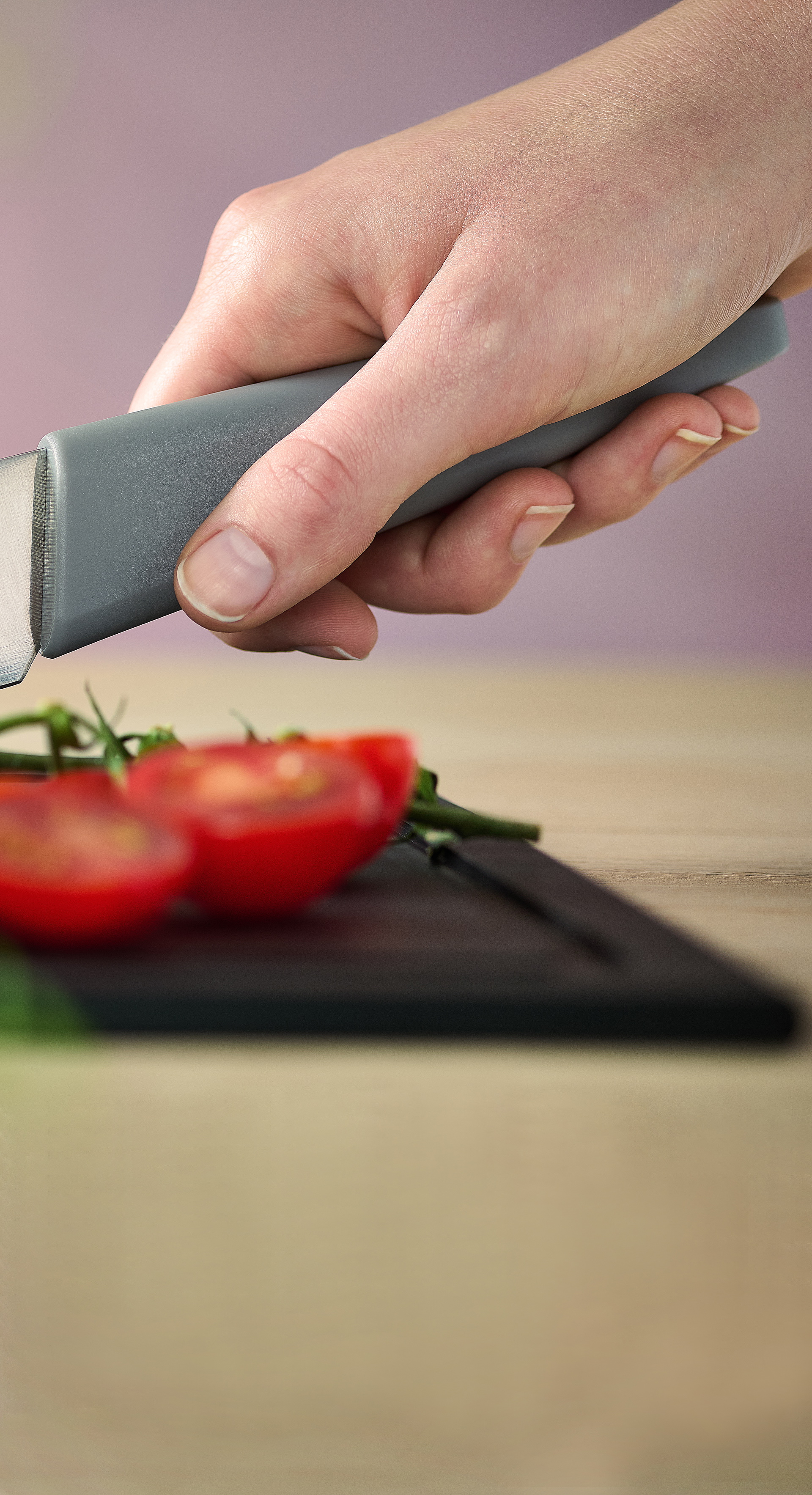 Mit dem Messer der Serie Cutting Edge werden mehrere Cherrytomaten auf einem Schneidebrett der Serie Cut & Serve halbiert.