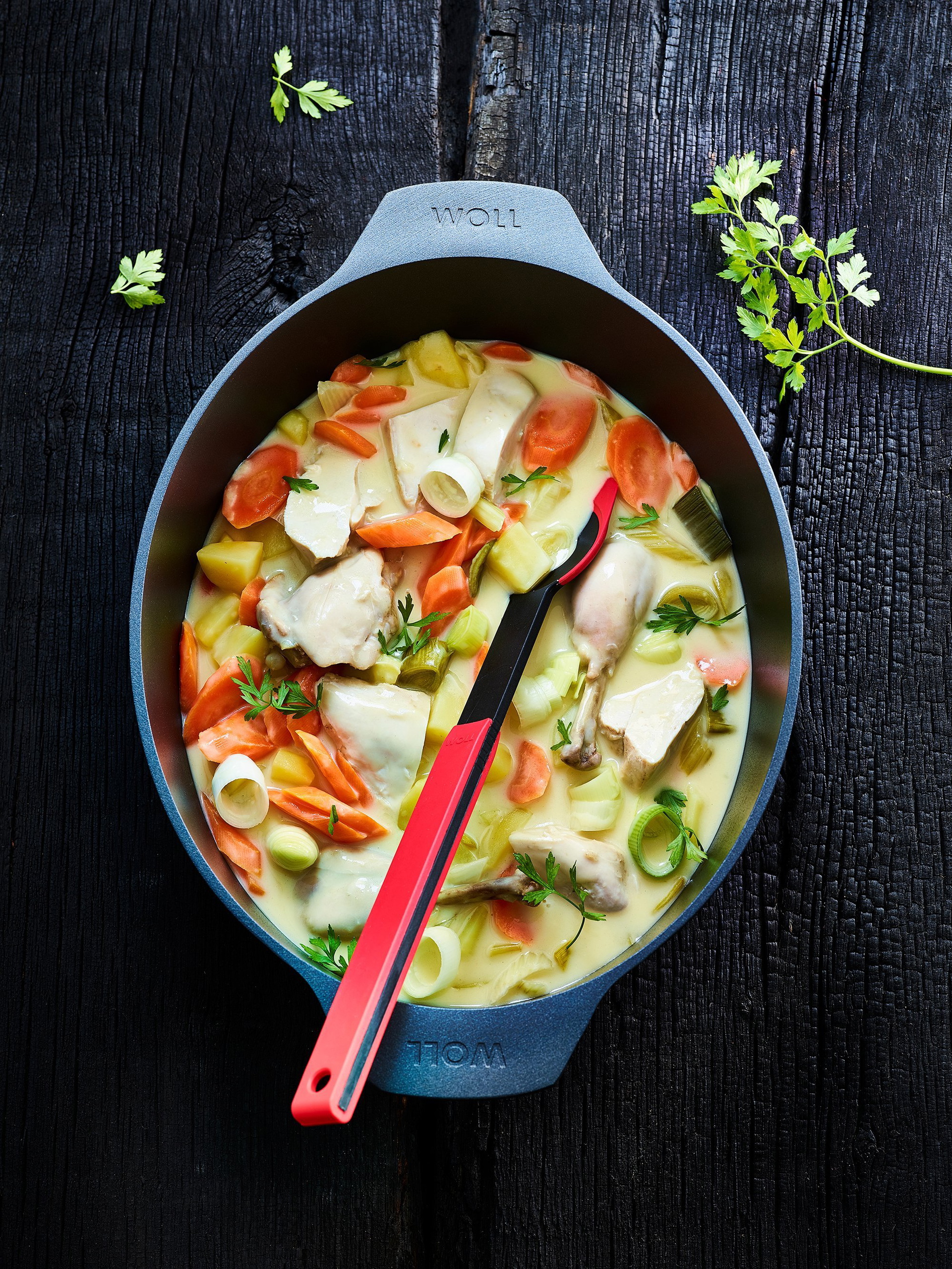 Diamond-Lite_3126DPI_beschwipstes_huhn_RGB In einem Diamond Lite Bräter befindet sich Geflügel und Gemüse. Mit einem Cock it Küchenhelfer wird alles umgerührt.