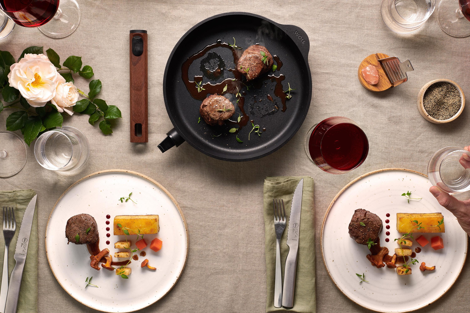 Auf dem Tisch steht eine runde Eco Logic QXR Pfanne, in der sich angebratenes Fleisch befindet.