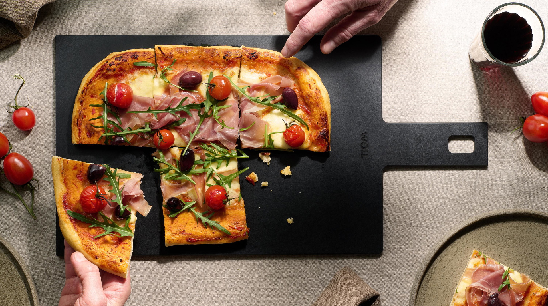 Auf dem Cut & Serve Schneidebrett mit Griff  liegen frisch gebackene Pizzastücke. 