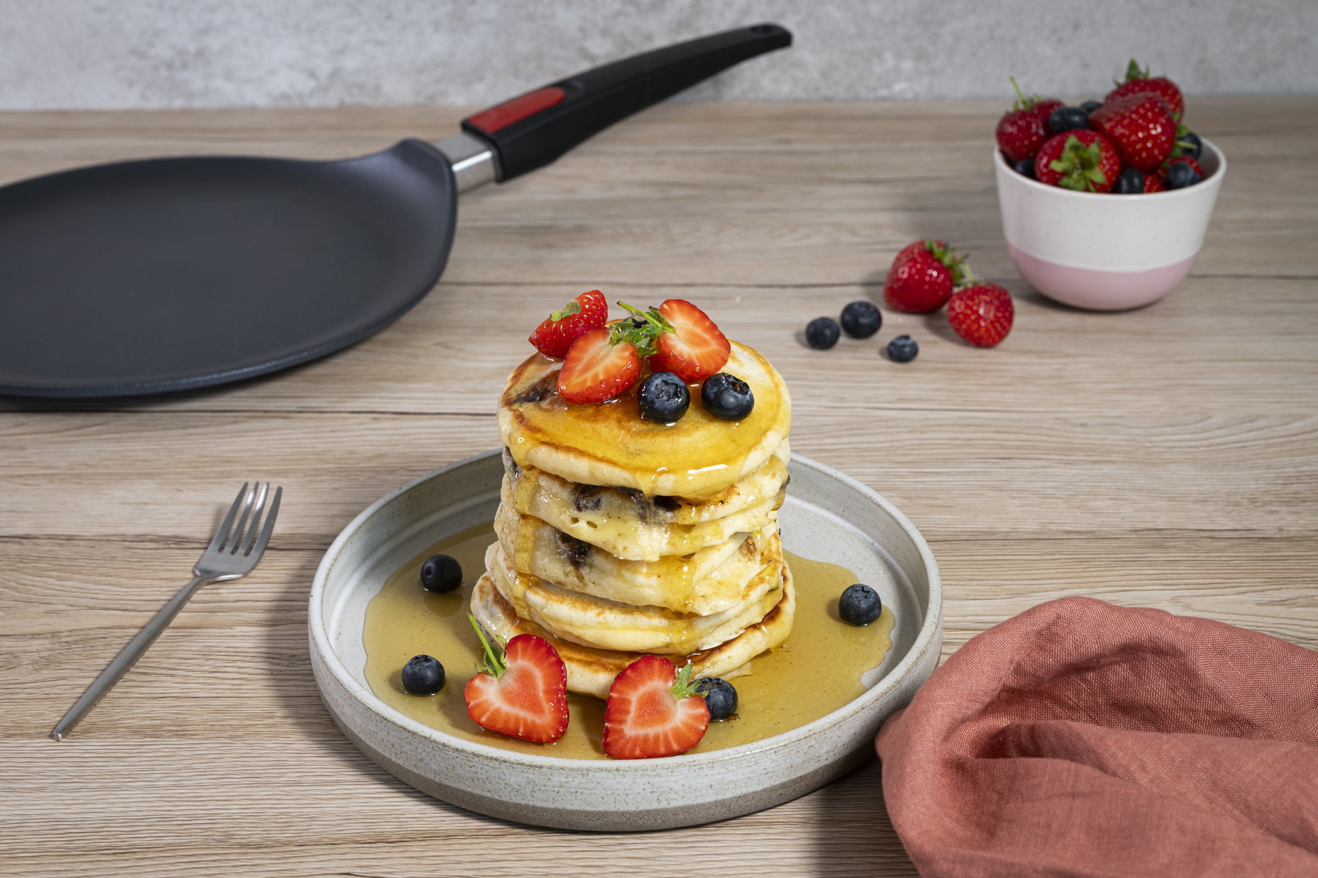 Diamond Lite Guss-Crêpepfanne Auf einem Teller liegt ein Stapel garnierte American Pancakes. Im Hintergrund steht eine Diamond Lite Crêpepfanne.