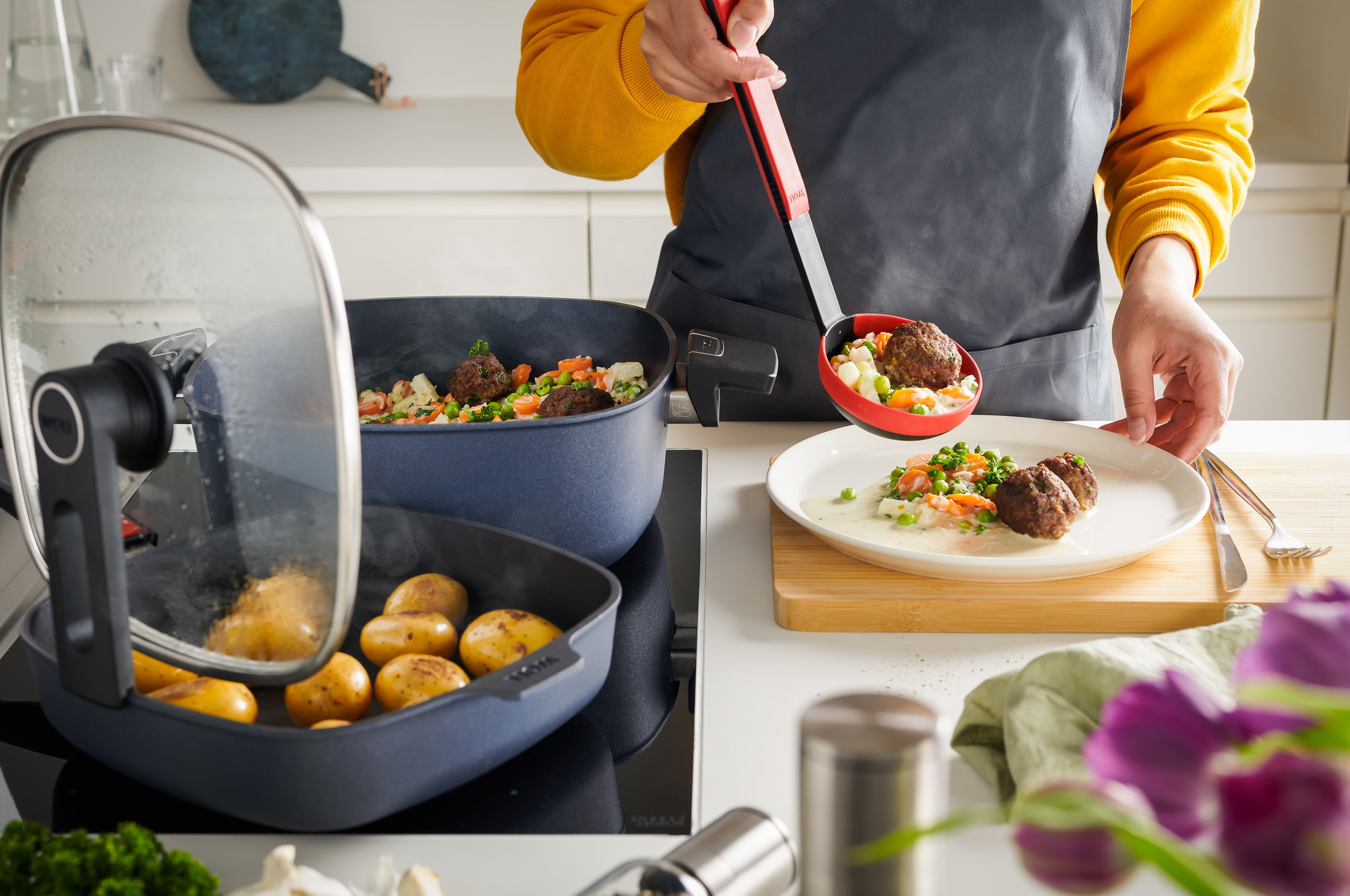 In der viereckigen Diamond Lite Kasserolle wird ein Wikinger-Eintopf zubereitet, während in der Pfanne Kartoffeln angebraten werden. Der Smart Lid steht auf der Pfannenkante.