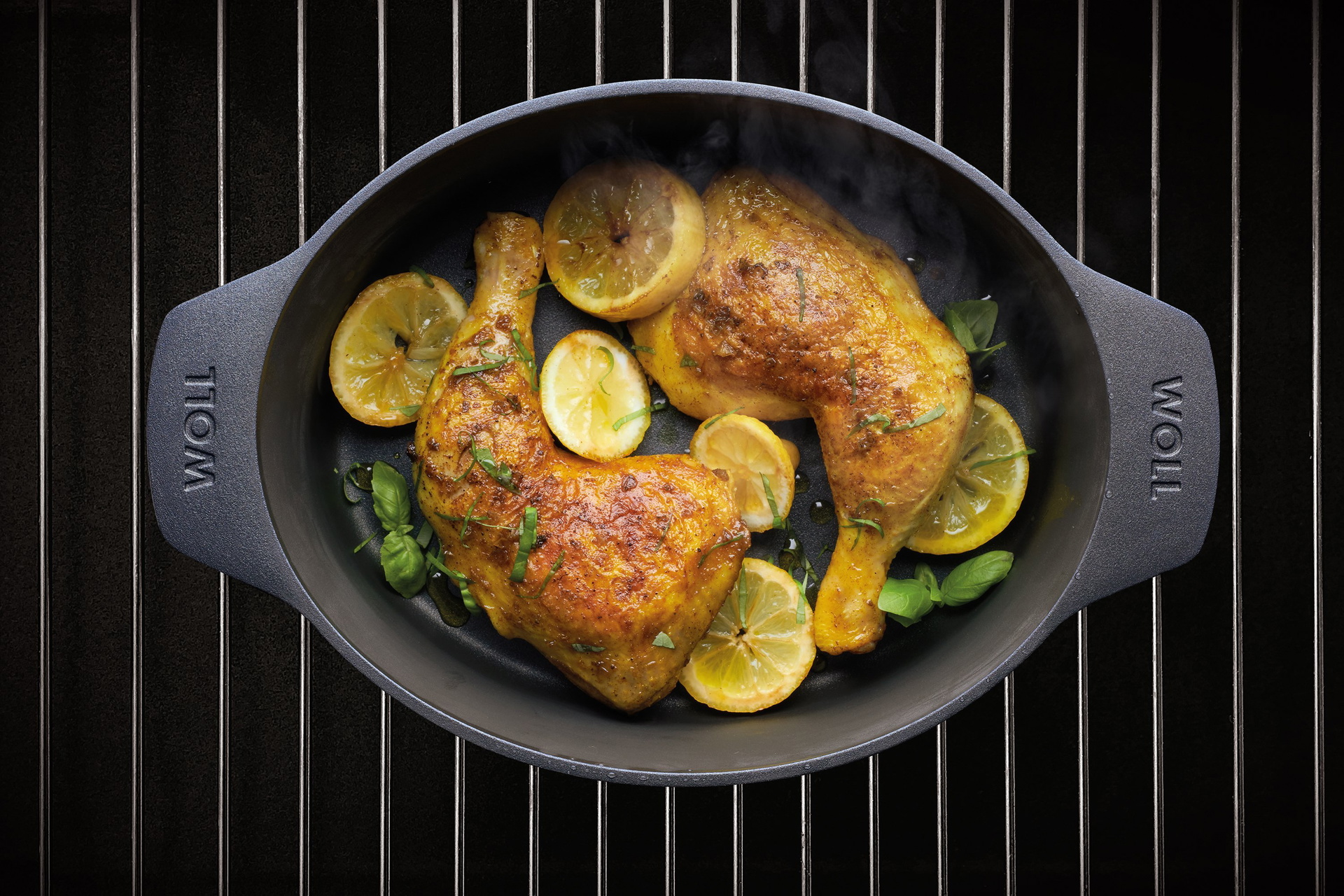 Auf einem Rost steht ein heißer Bräter aus der Serie Diamond Lite. In diesem befinden sich Maishähnchenkeulen mit Zitrone und Basilikum.