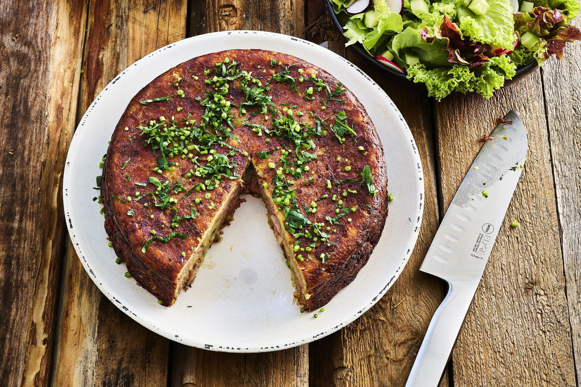 Auf einem Teller liegt eine frisch gebackene Kartoffellasagne nach saarländischer Art. Mit einem Messer der Serie Edge wurde bereits ein Stück davon genommen.