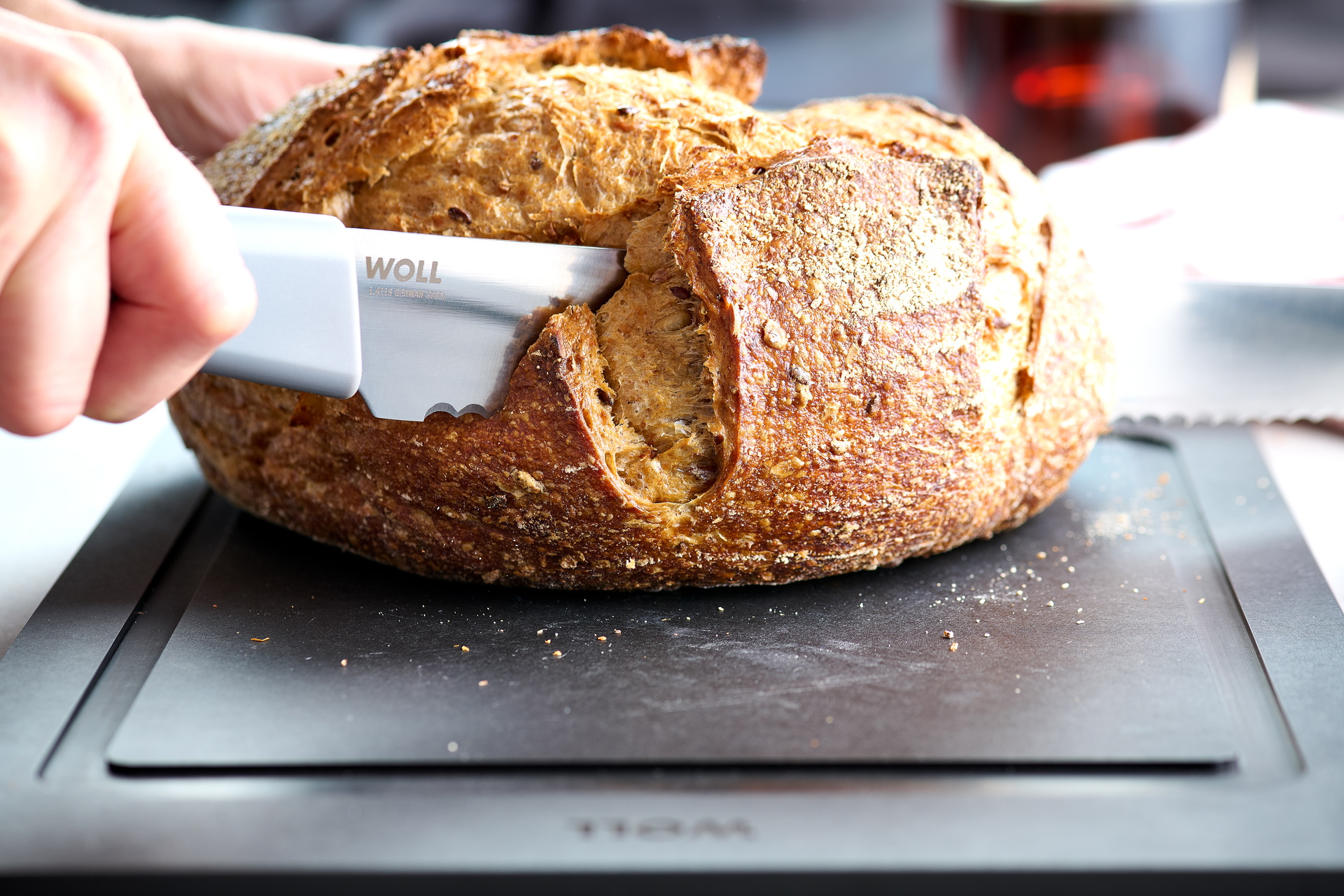 Mit einem Cutting Edge Messer wird ein Brotlaib auf einem Cut & Serve Schneidebrett geschnitten.