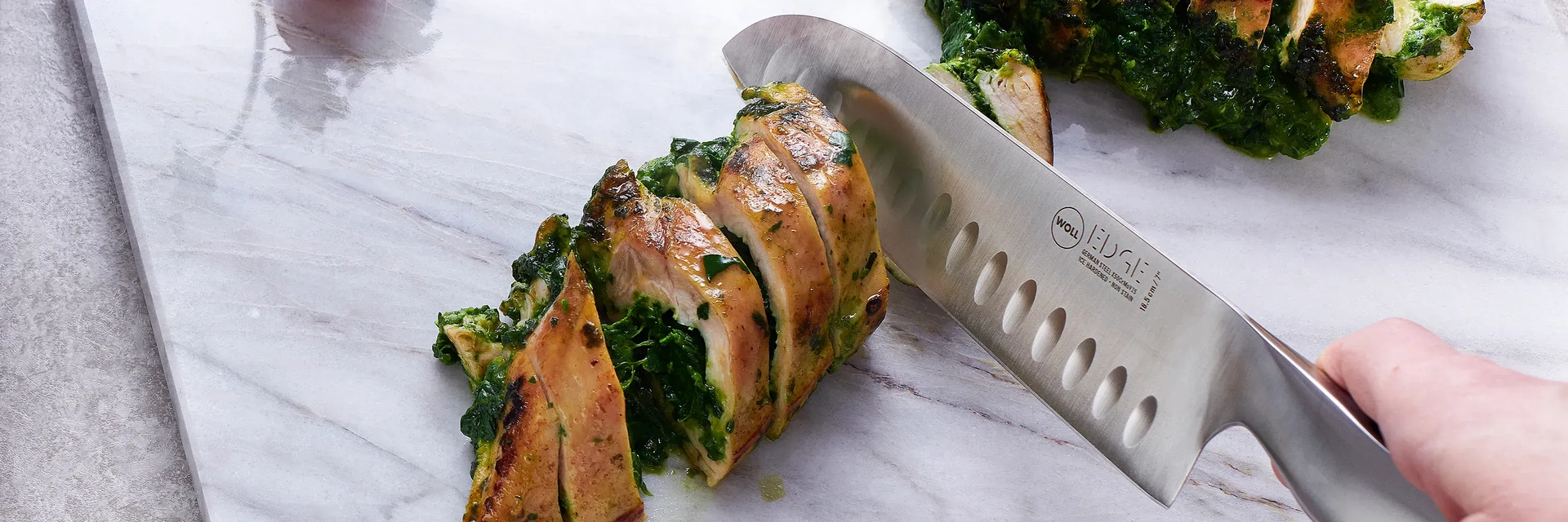 Mit einem Messer der Serie „Edge“ wird eine mit Spinat gefüllte Fleischrolle auf dem Schneidebrett in Portionsgrößen geschnitten.