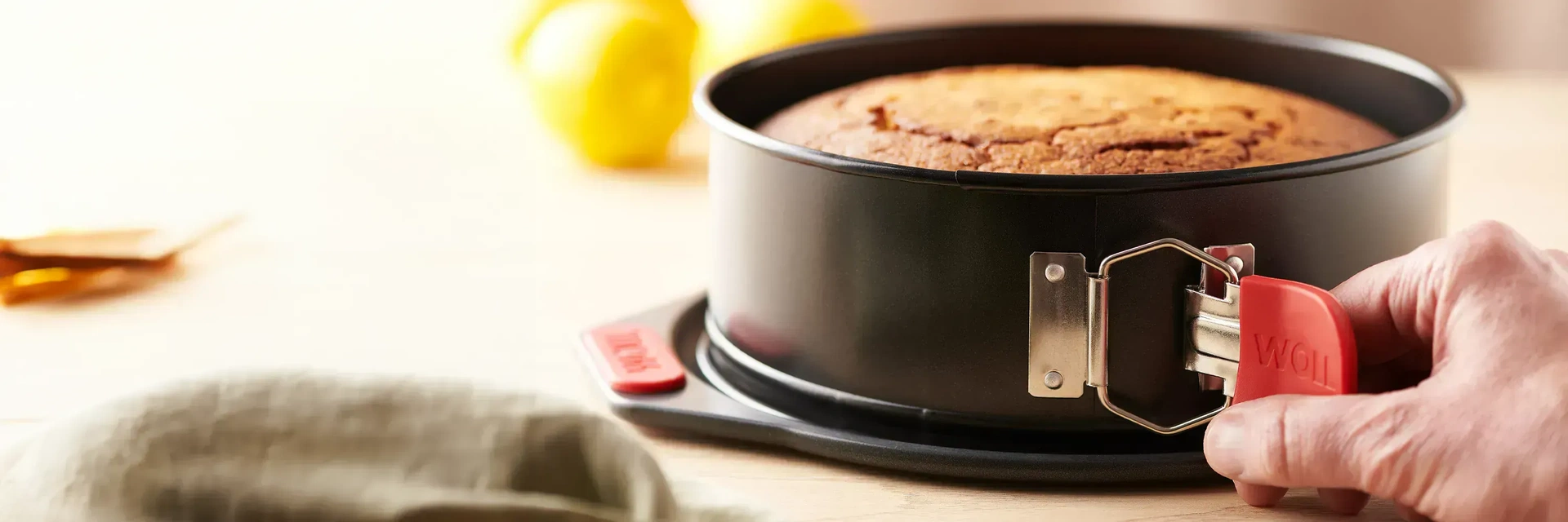 Die runde Springform der Serie Let's Bake enthält einen fertig gebackenen Kuchen. Im Hintergrund sind Zitronen zu sehen.
