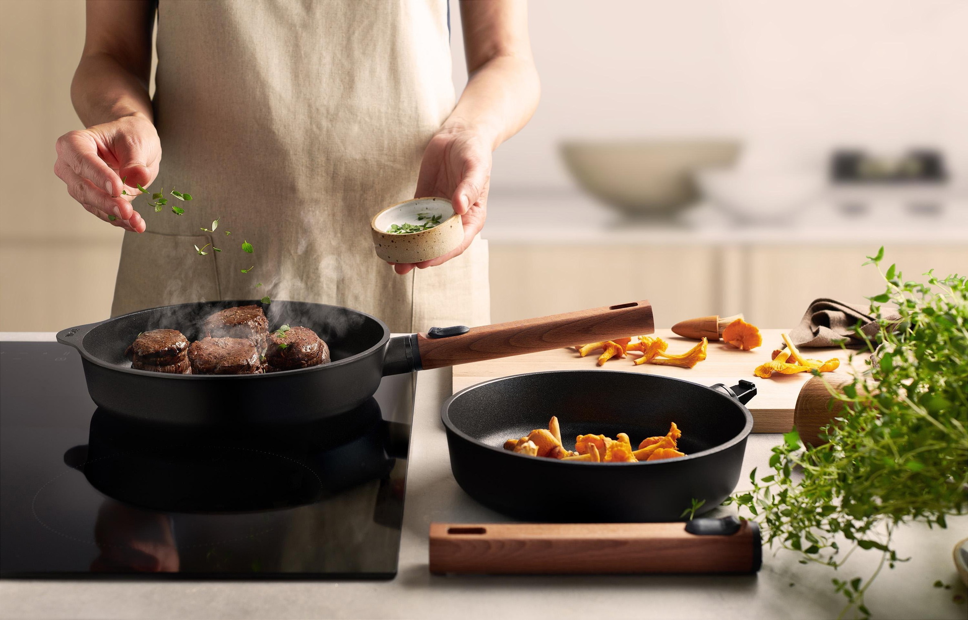 In einer runden Eco Logic QXR-Pfanne wird Fleisch angebraten. In der Pfanne daneben liegen Pfifferlinge.