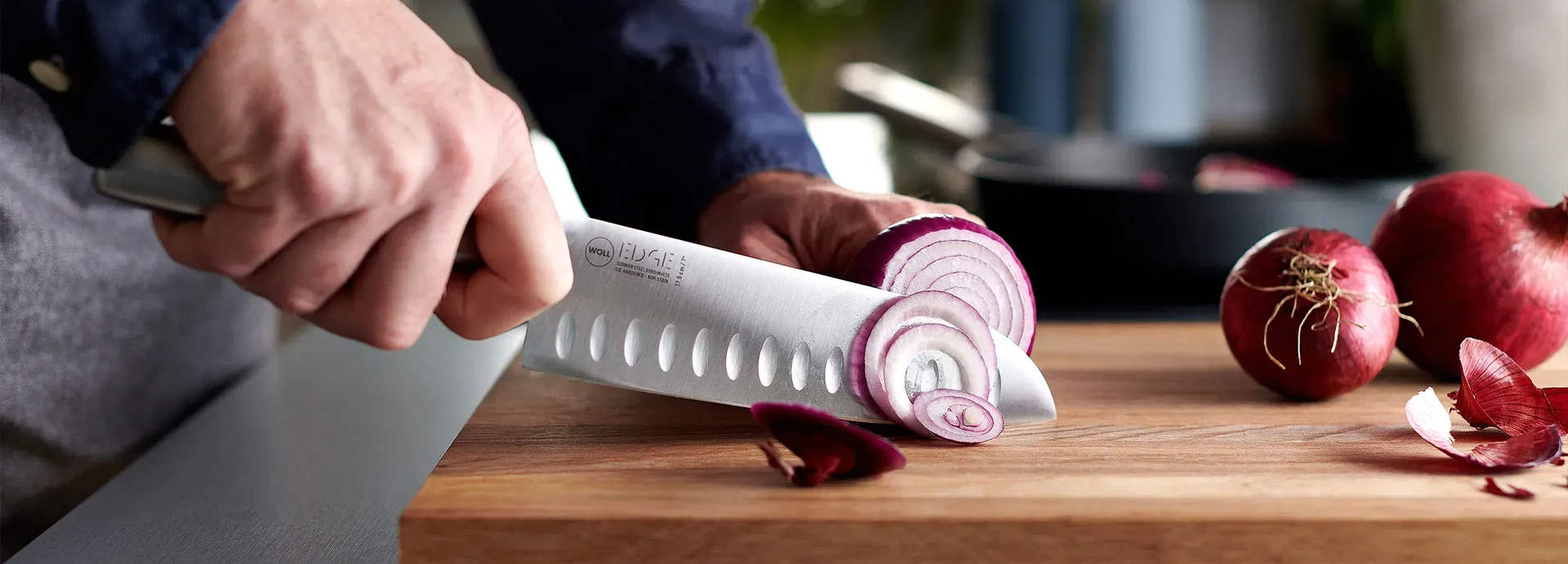 Auf einem Schneidebrett werden Zwiebeln mithilfe des Santokumessers der Serie Edge in dünne Scheiben geschnitten.