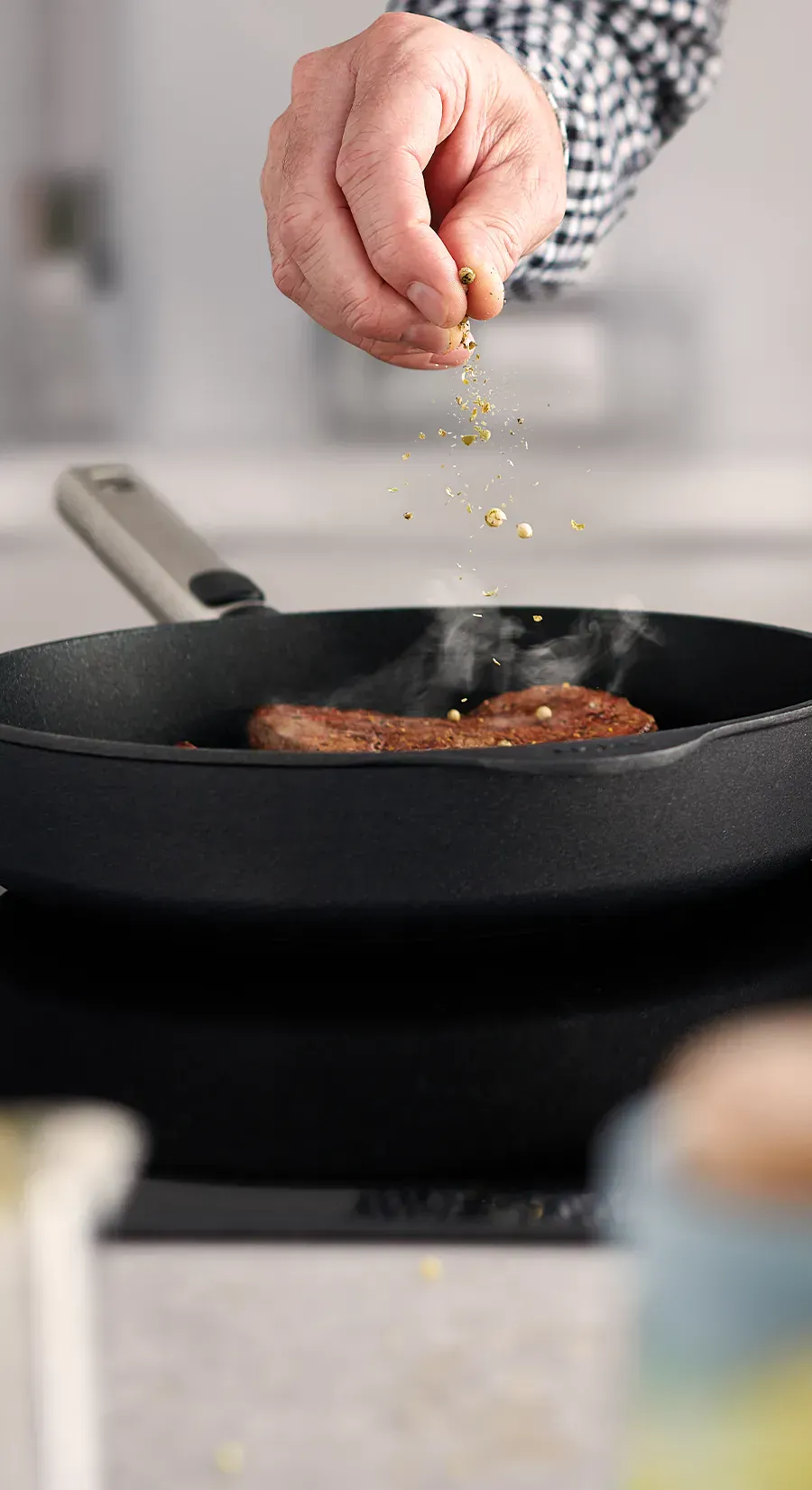 In einer heißen, runden Logic-Pfanne wird frisches Fleisch angebraten. Dieses wird mit Kräutersalz garniert.