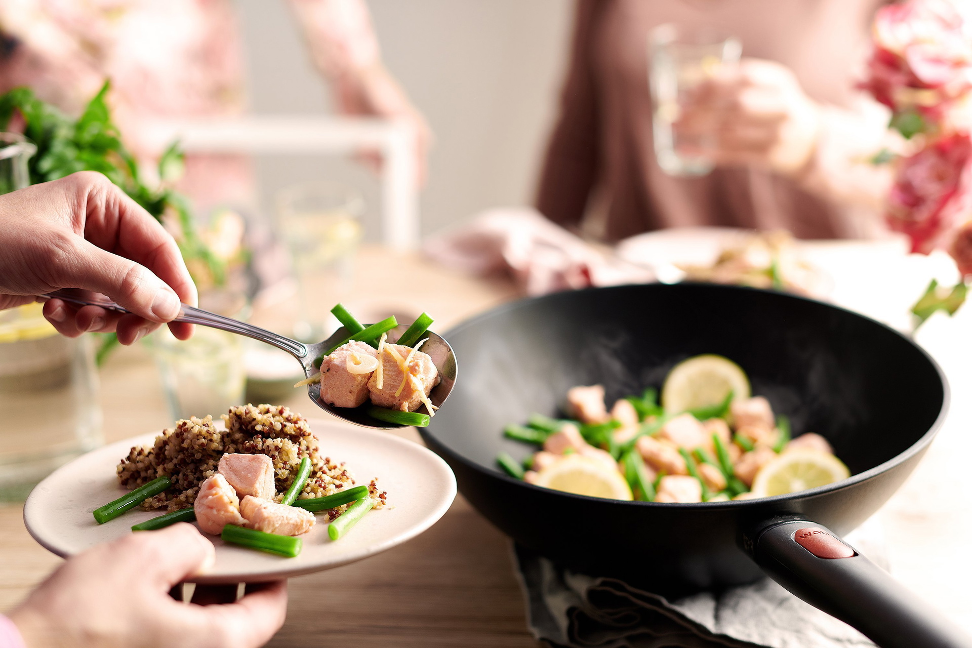 In einer runden Wok- und Rührpfanne der Serie Eco Lite QXR wurde frischer Lachs mit grünen Bohnen zubereitet. Anschließend wird eine Portion auf einen Teller gegeben.