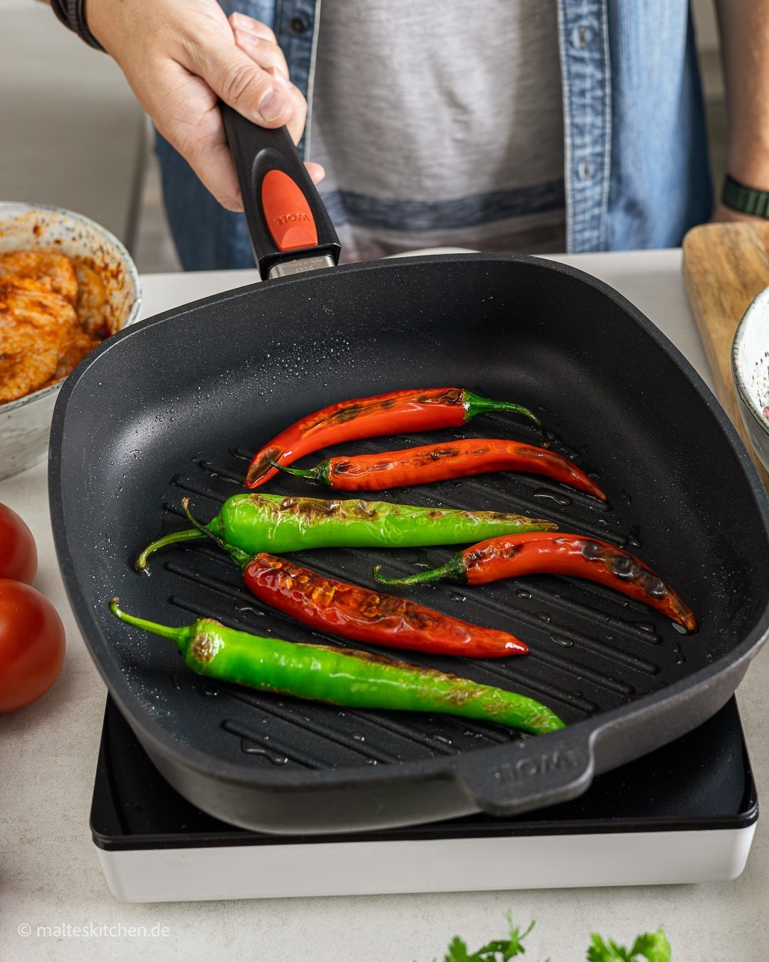 In einer viereckigen Titan Best Grillpfanne werden Peperonis angebraten.