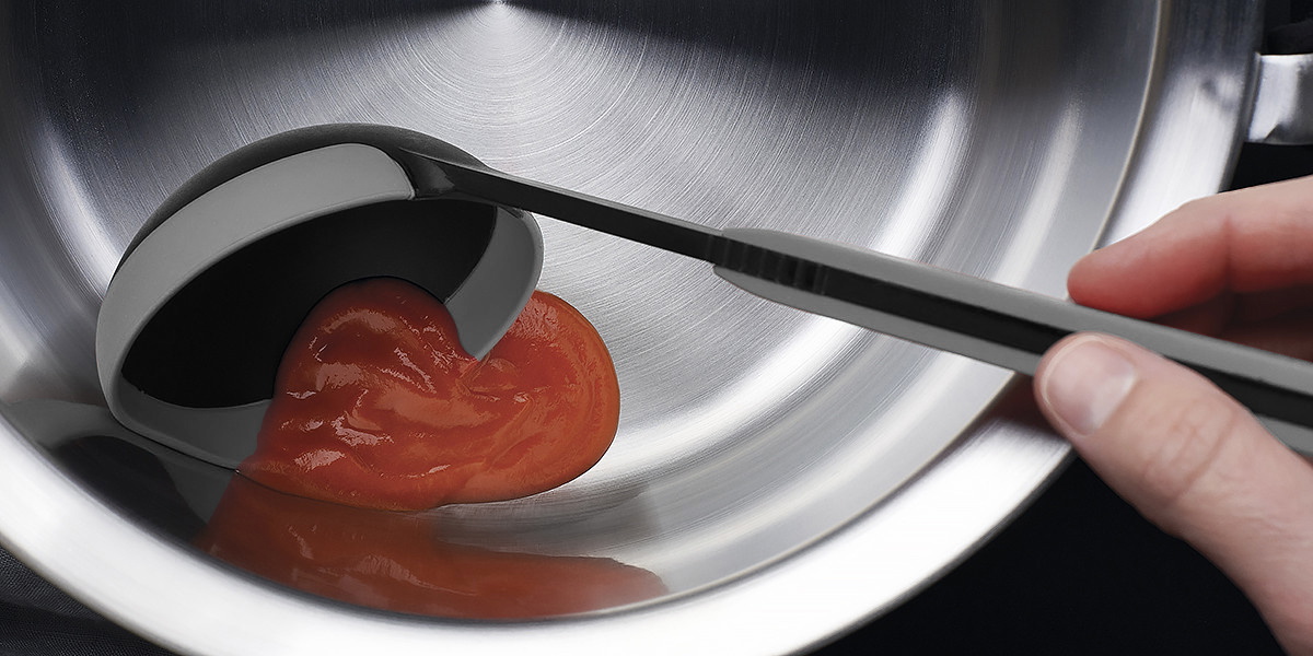 Die Tomatensoße wird mithilfe der grauen Cock it Schöpfkelle in eine silberne Schüssel gegeben.