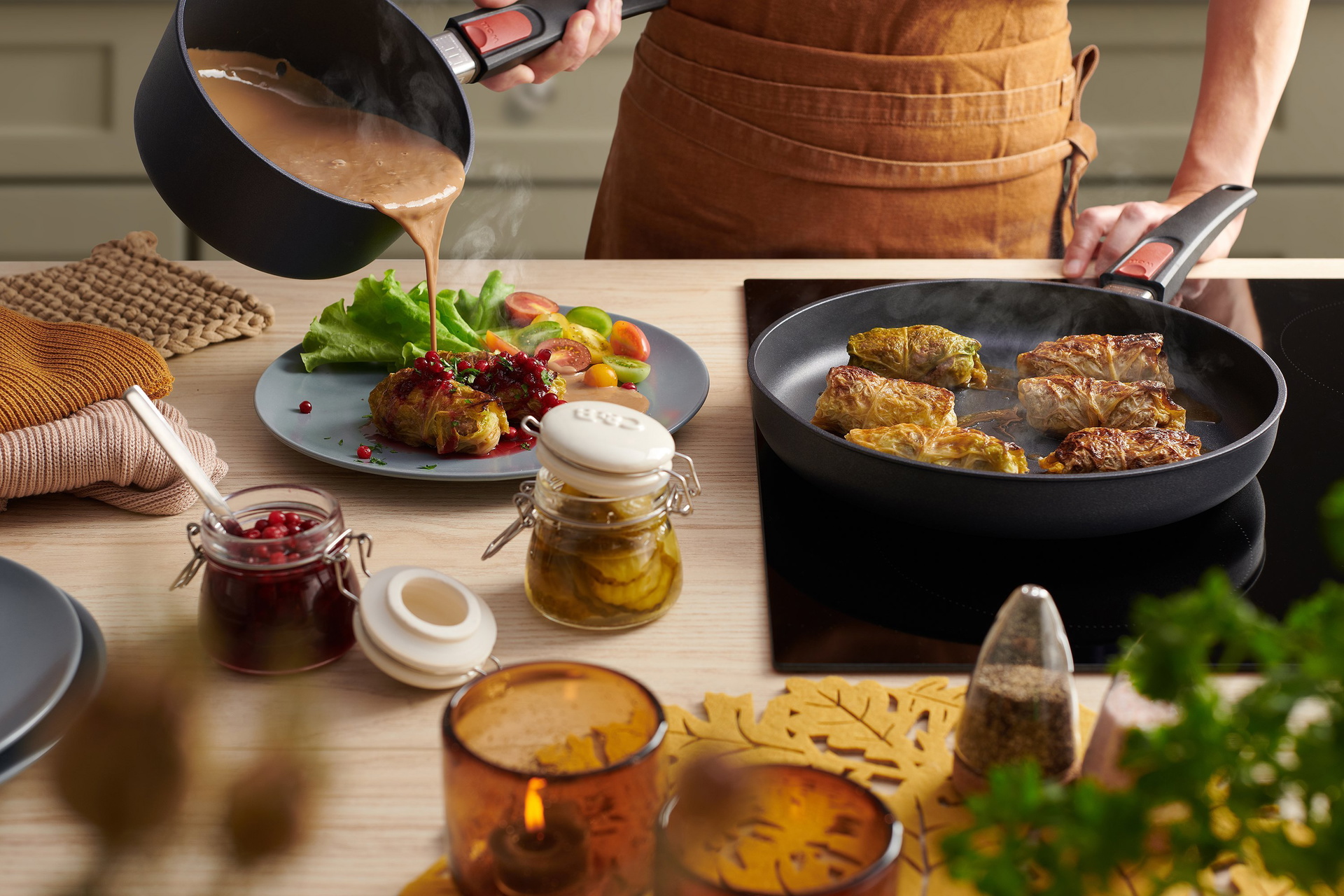 In einer heißen, runden Diamond-Lite-Pfanne mit abnehmbarem Stiel werden Kåldolmar, schwedische Kohlrouladen, angebraten. Die Kohlrouladen werden mit Gemüse und Salat auf einem daneben stehenden Teller angerichtet. Aus einem Stieltopf derselben Serie mit