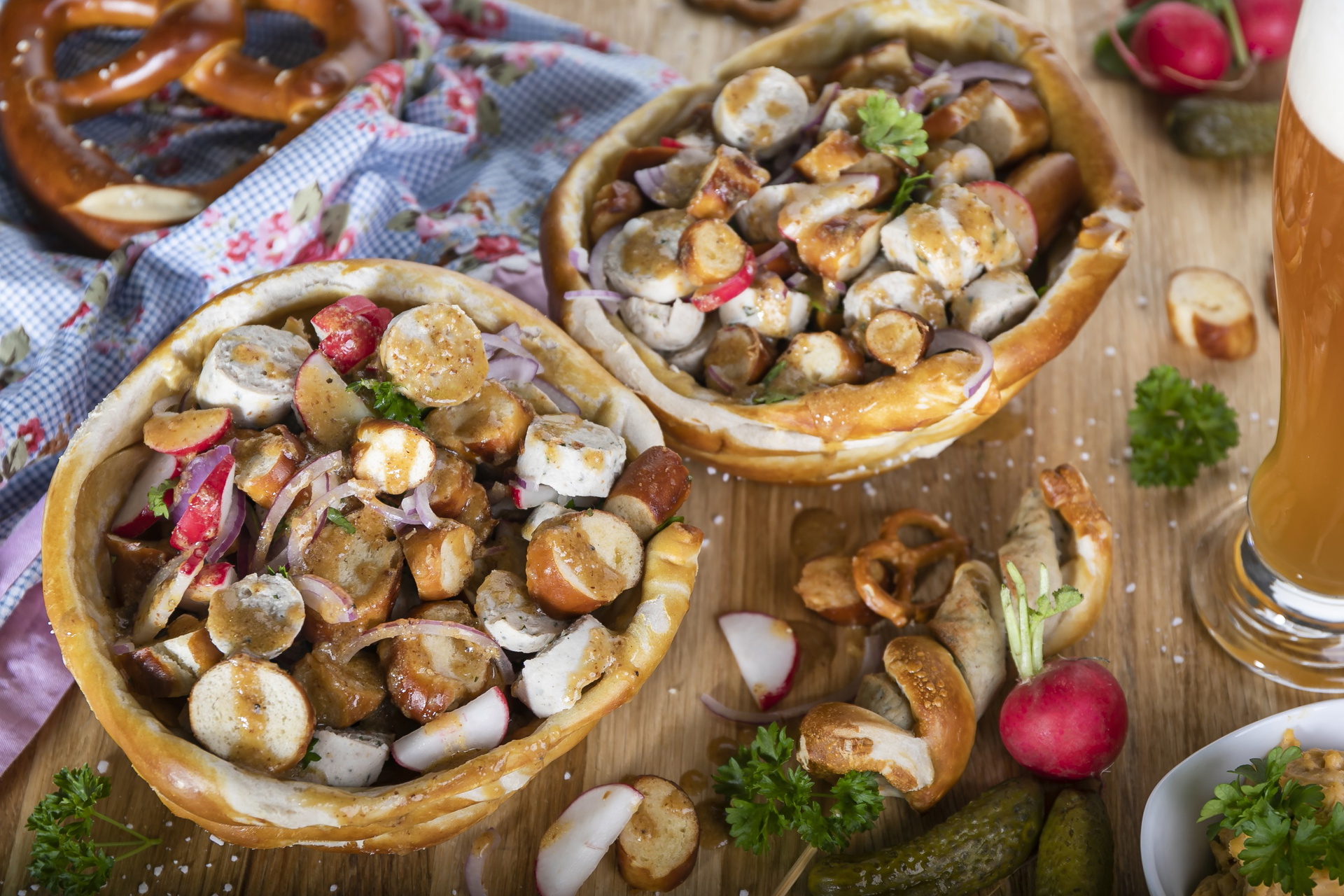 Auf einem Brett stehen zwei Weisswurstsalate, daneben Bier und weitere Zutaten.