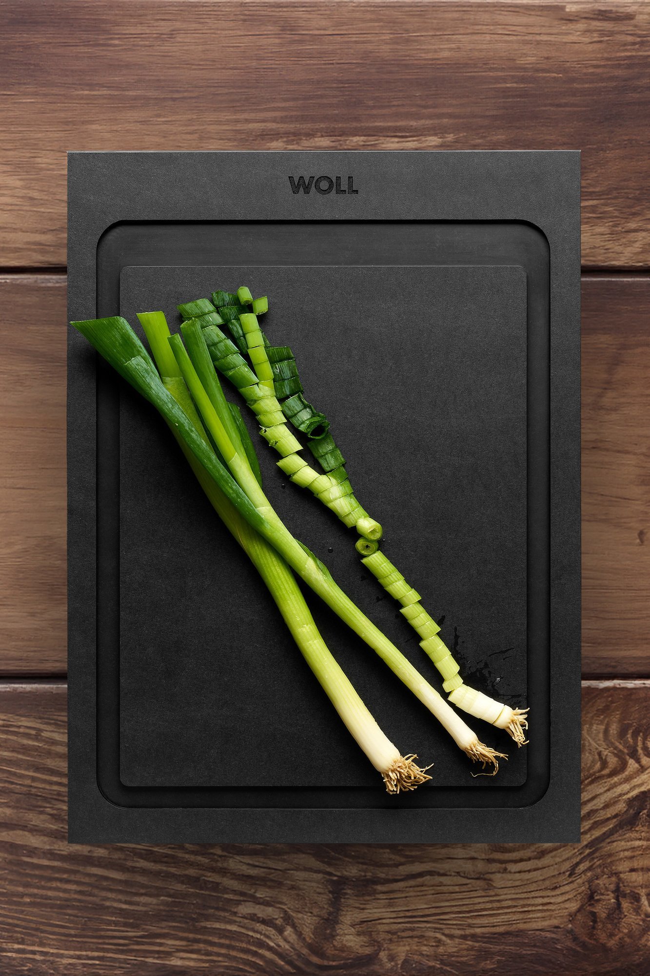 Auf einem Cut & Serve Schneidebrett mit Saftrinne liegen Frühlingszwiebeln.