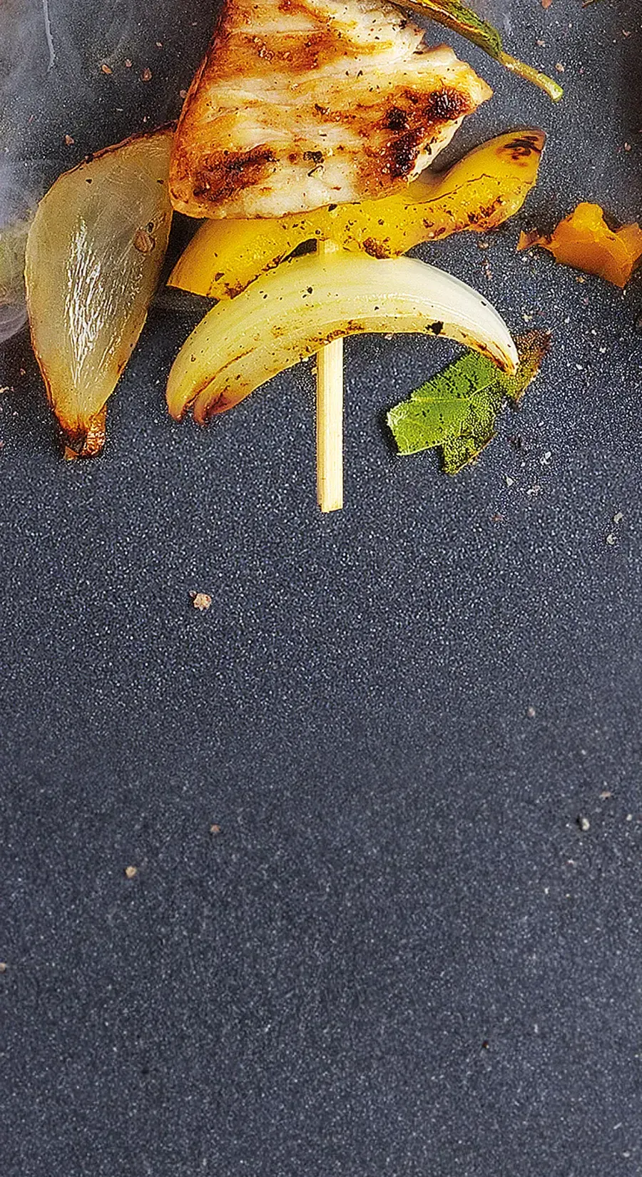 Detailaufnahme eines Spießes, der in der Pfanne angebraten wird.