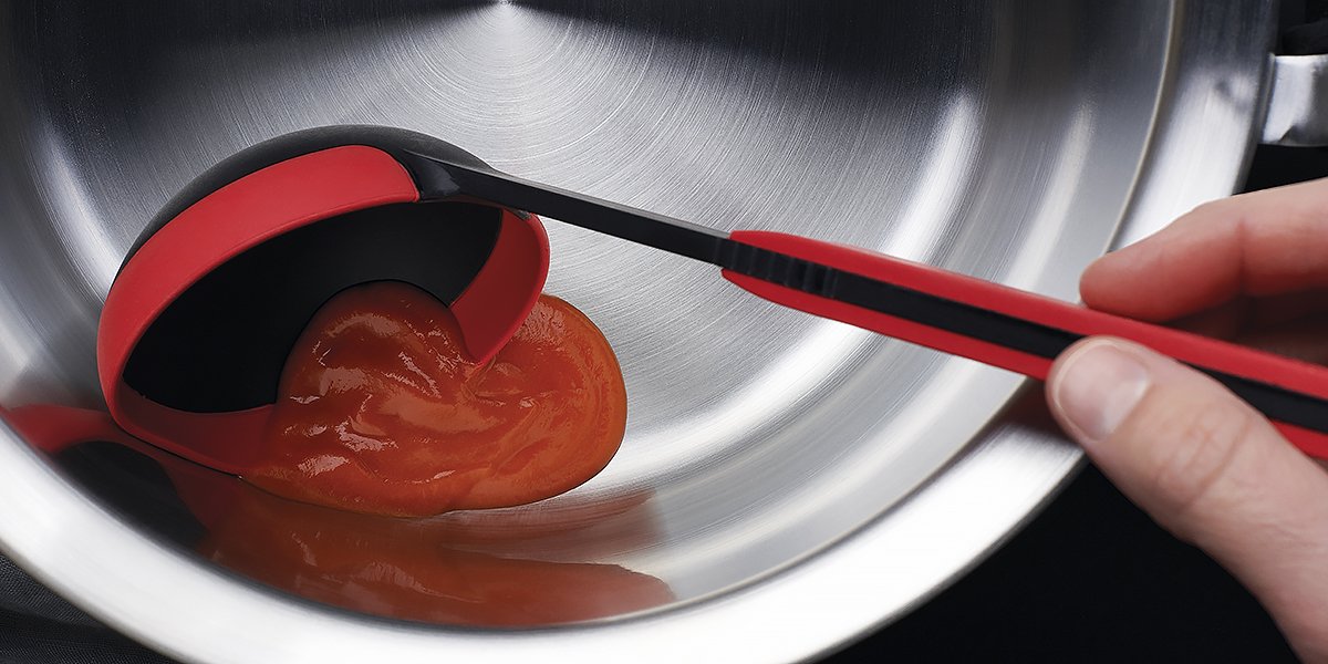 KU008_Mood_1200x600_RGB Die Tomatensoße wird mithilfe der roten Cock it Schöpfkelle in eine silberne Schüssel gegeben.