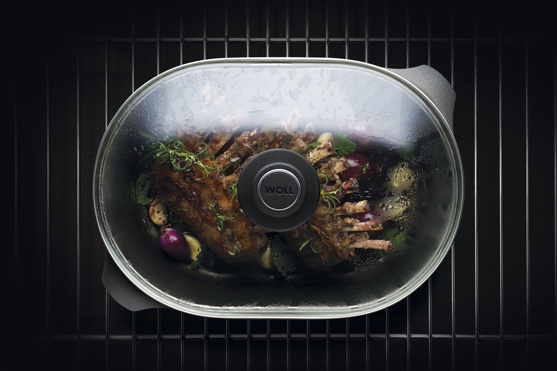 Auf dem Rost steht ein Titan Best Bräter mit Glasdeckel in der Fleisch zubereitet wird.