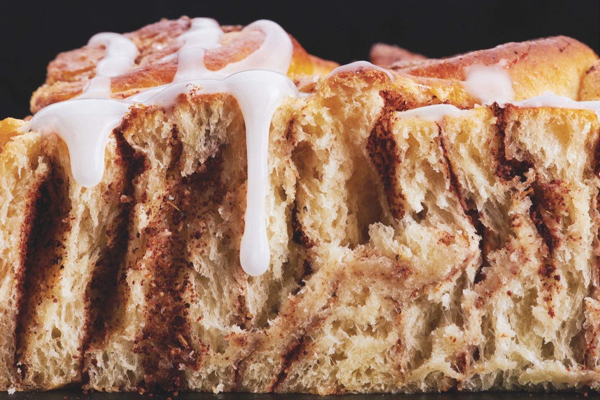 Im Querschnitt sieht man eine Zimtschnecke mit Kardamom mit Topping.