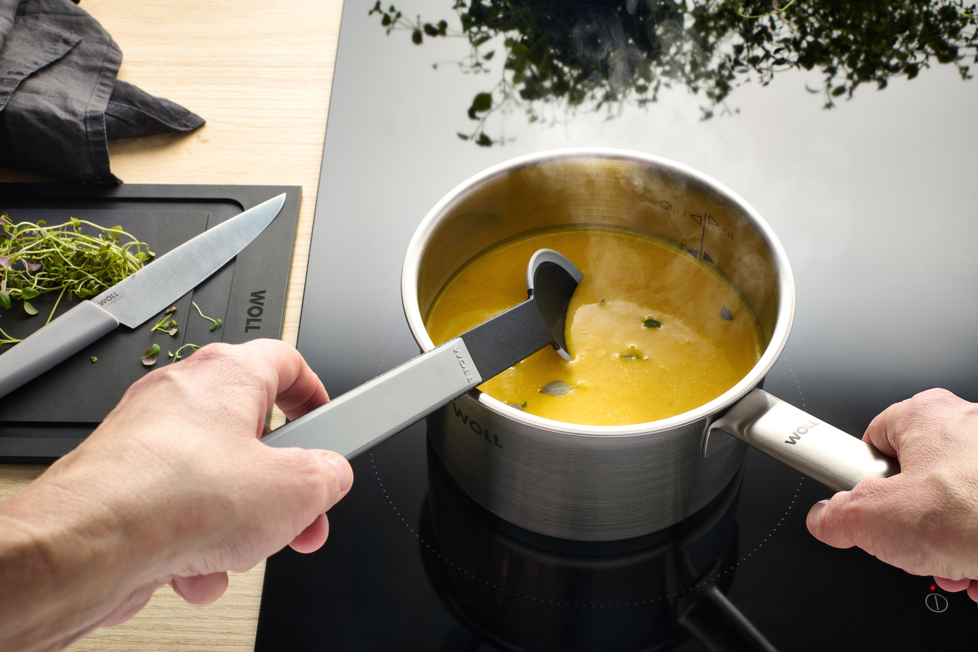 Auf dem Herd steht ein Steel Stieltopf in der Suppe mit einem Cock it Kochlöffel umgerührt wird.
