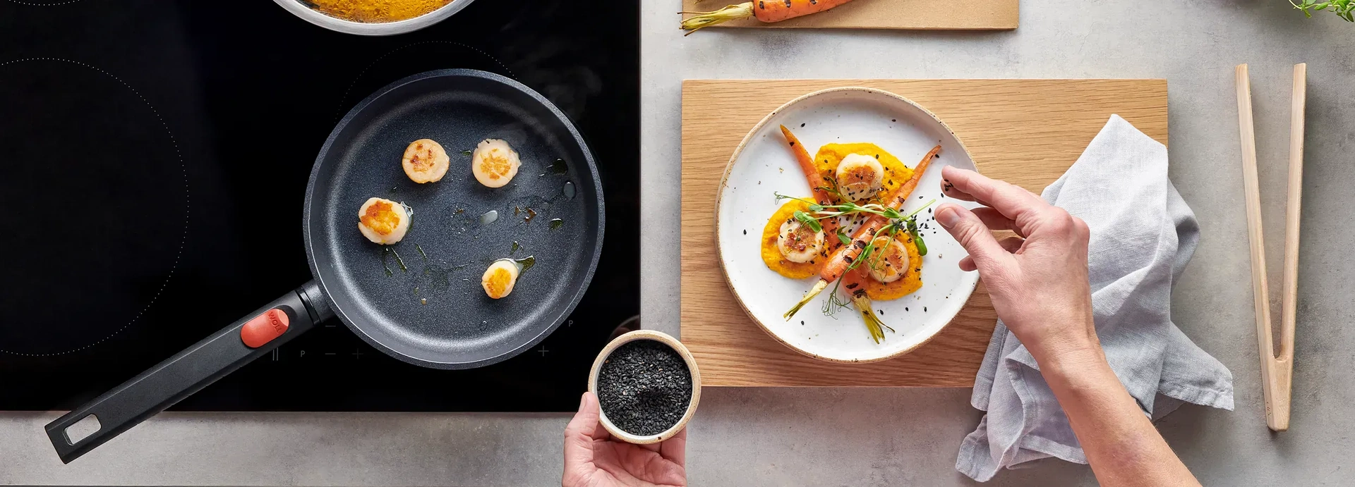 Die Jakobsmuscheln wurden in einer heißen, runden Pfanne der Serie Eco Logic QXR angebraten. Auf einem Teller, der neben dem Herd bereitsteht, werden sie auf einem Bett aus Karottenpüree serviert und mit einer halbierten, angebratenen Karotte garniert.