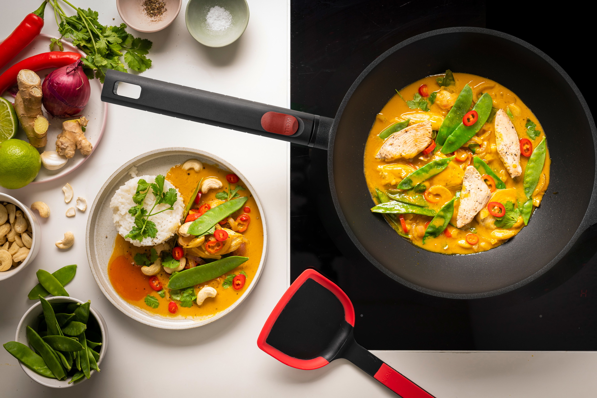 Eco Logic QXR Guss-Wok Auf dem Herd steht eine runde Logic XR Wok- und Rührpfanne, in der Curryhähnchen zubereitet wird.