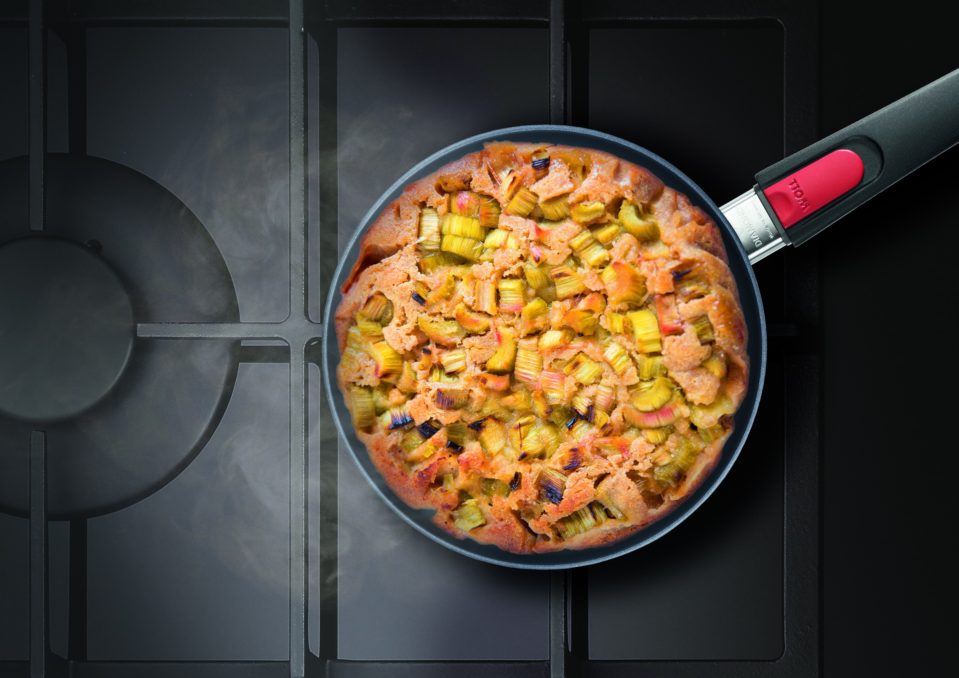 Auf dem Herd steht eine runde, heiße Diamond-Lite-Pfanne mit abnehmbarem Stiel, in der sich frisch zubereitete, dampfende Rhabarbertarte befindet.