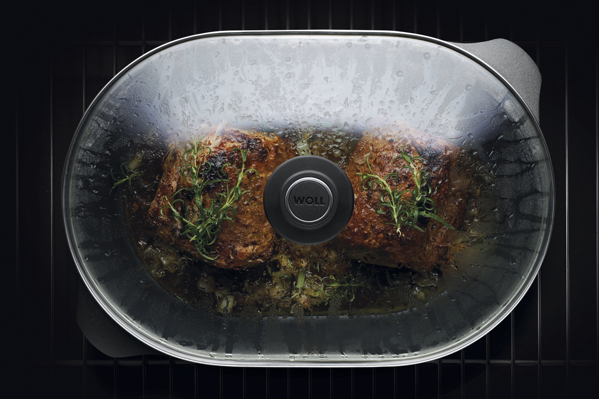 Auf dem Rost steht ein Titan Best Bräter mit Glasdeckel in der Fleisch zubereitet wird.